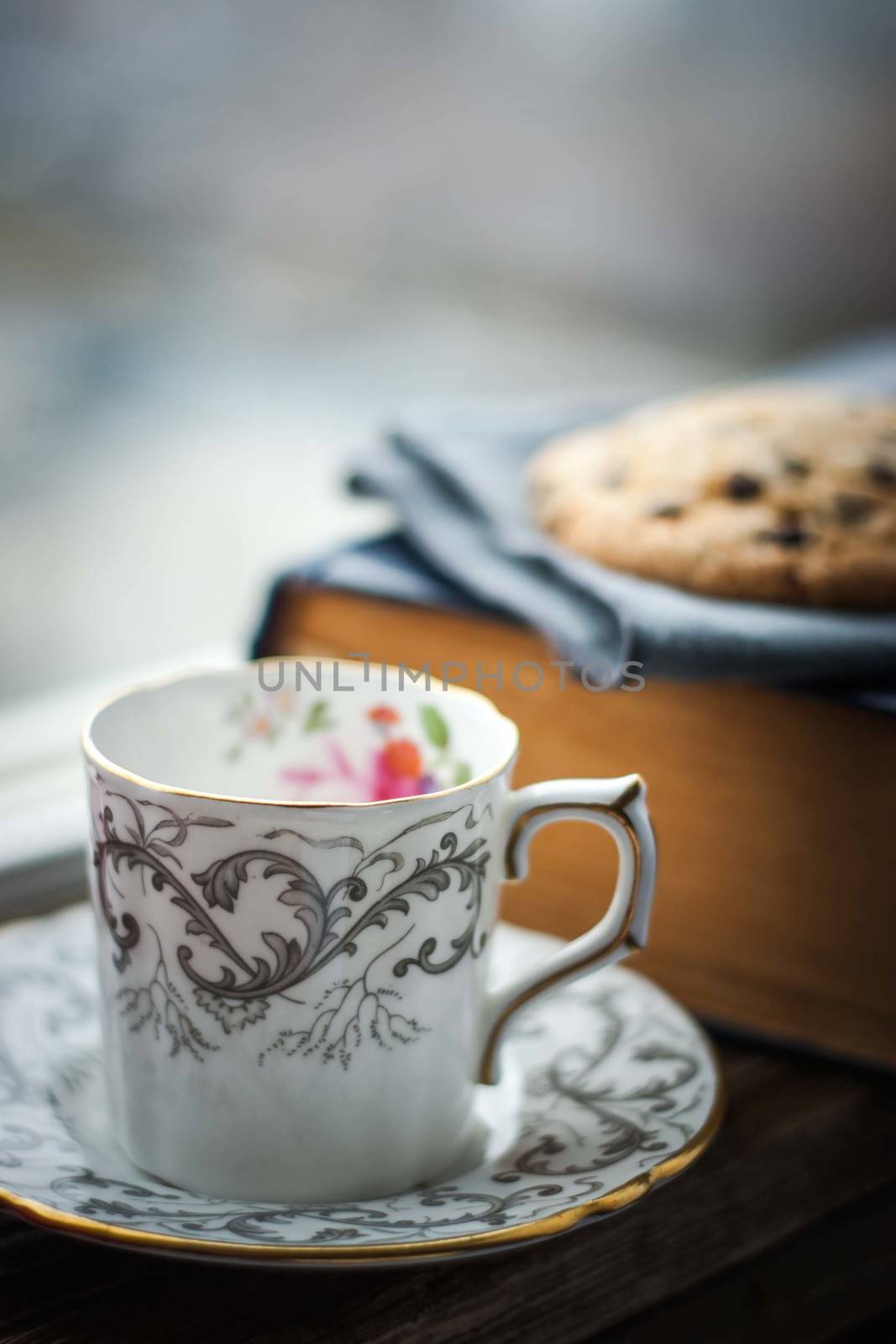 Coffee cup  with blurred cookies and old book