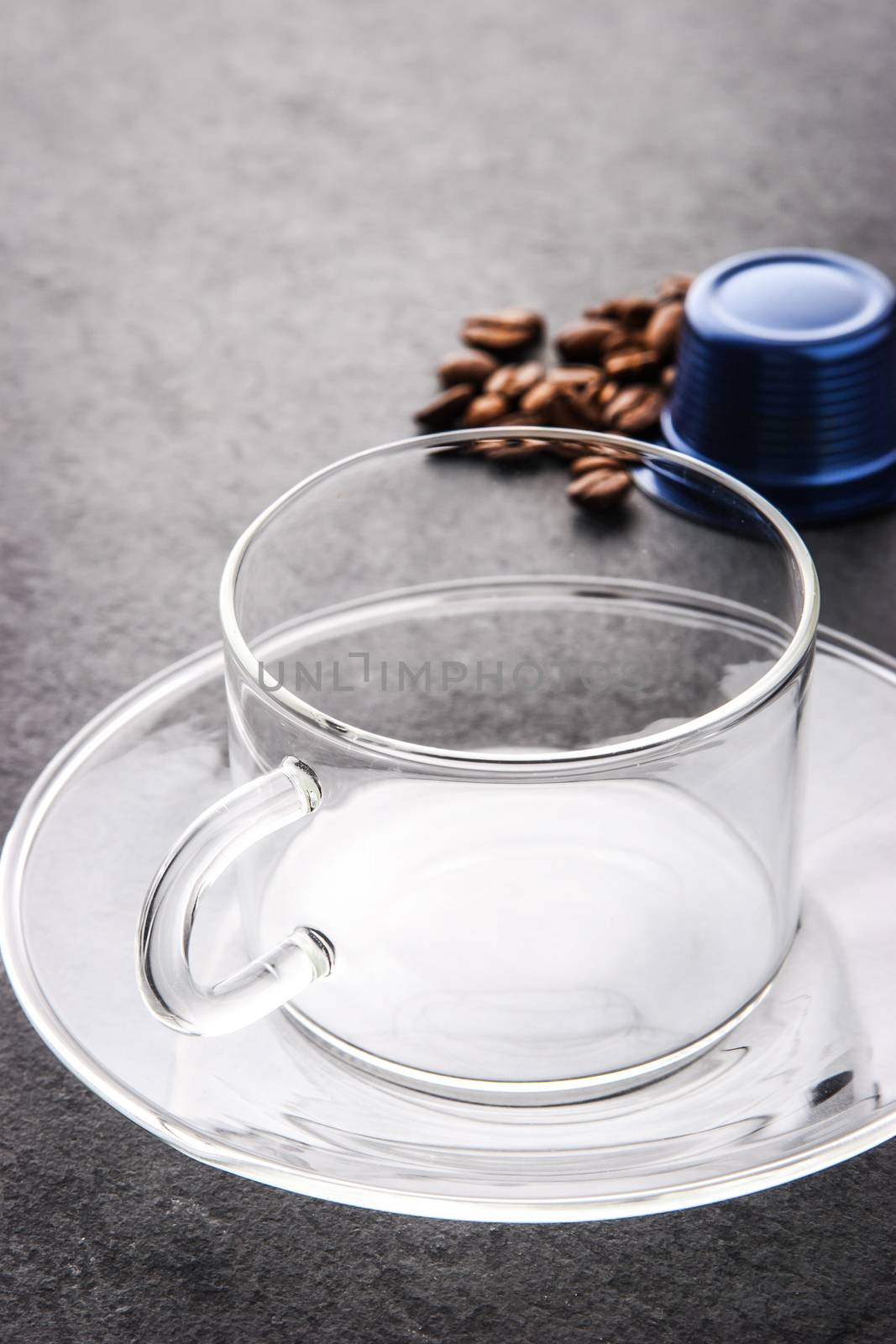 Glass cup with coffee capsule and coffee beans vertical