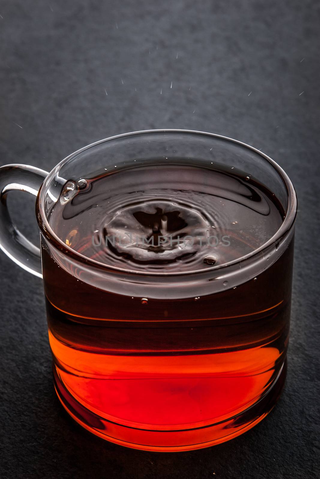 Glass cup of tea  with falling drop