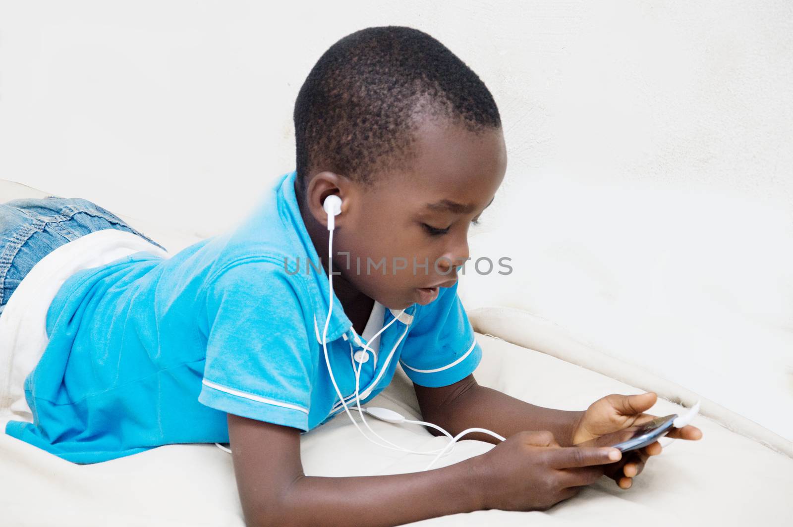 This child focused on the mobile phone, listening to music with headphone.