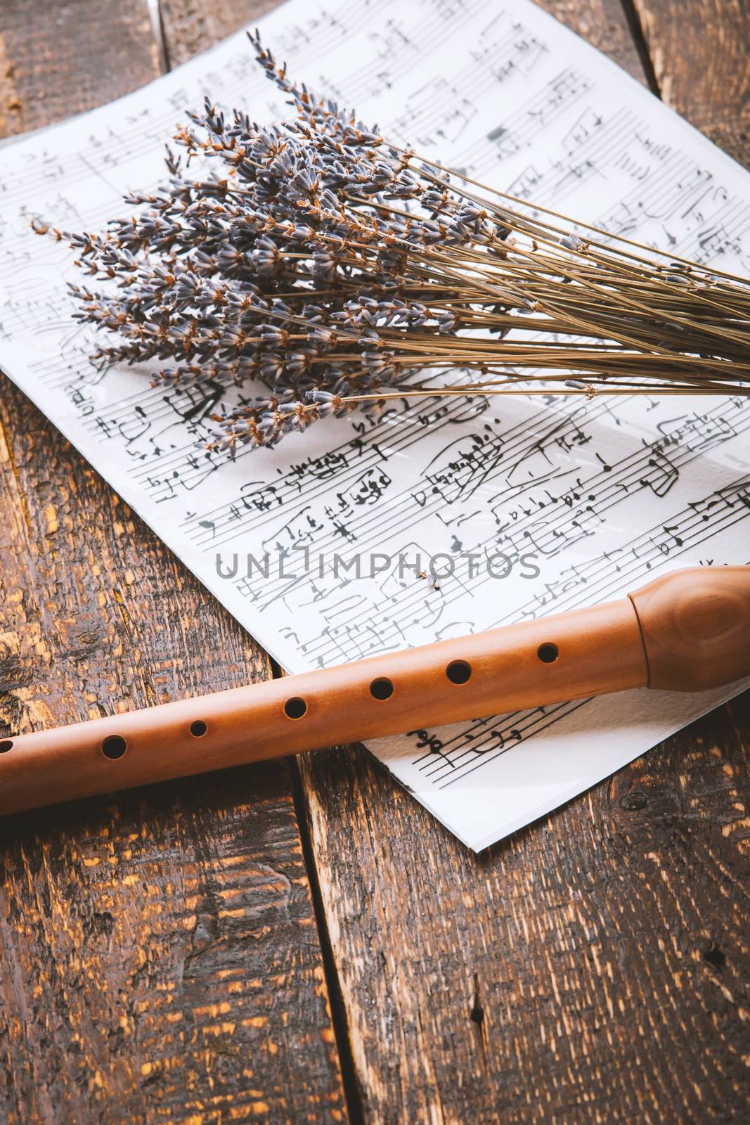 Flute with notes and lavender on the wooden table vertical
