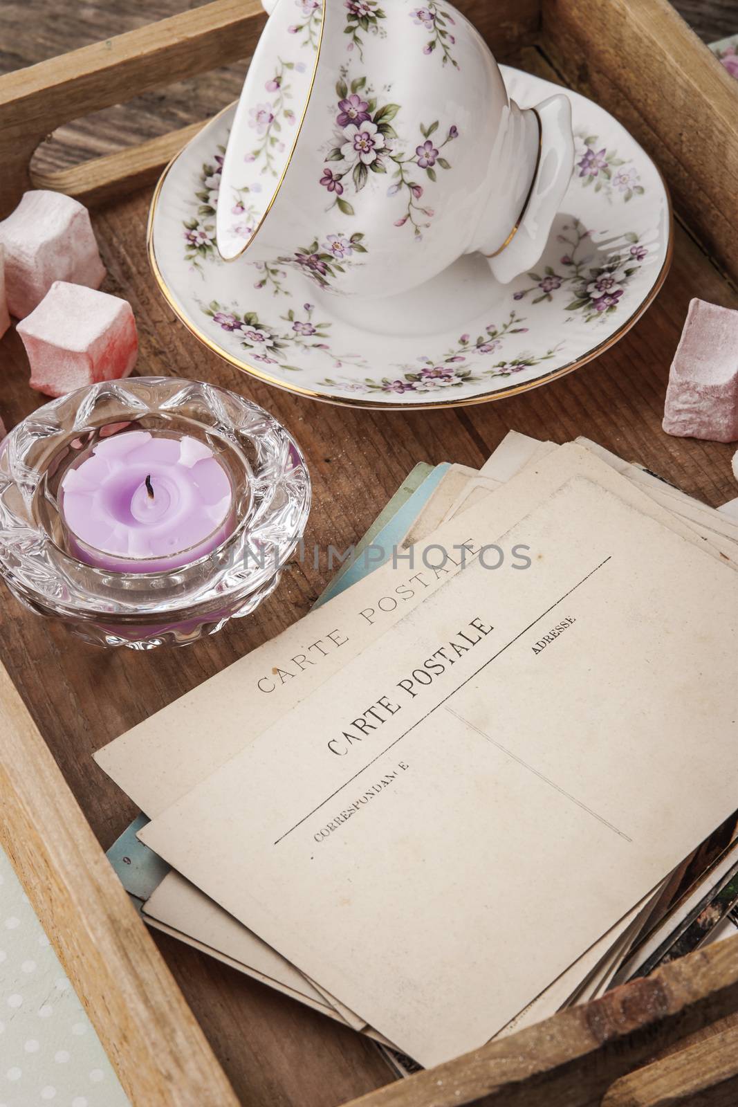 Tea things with sweets and postcards on the wooden tray verticalФС