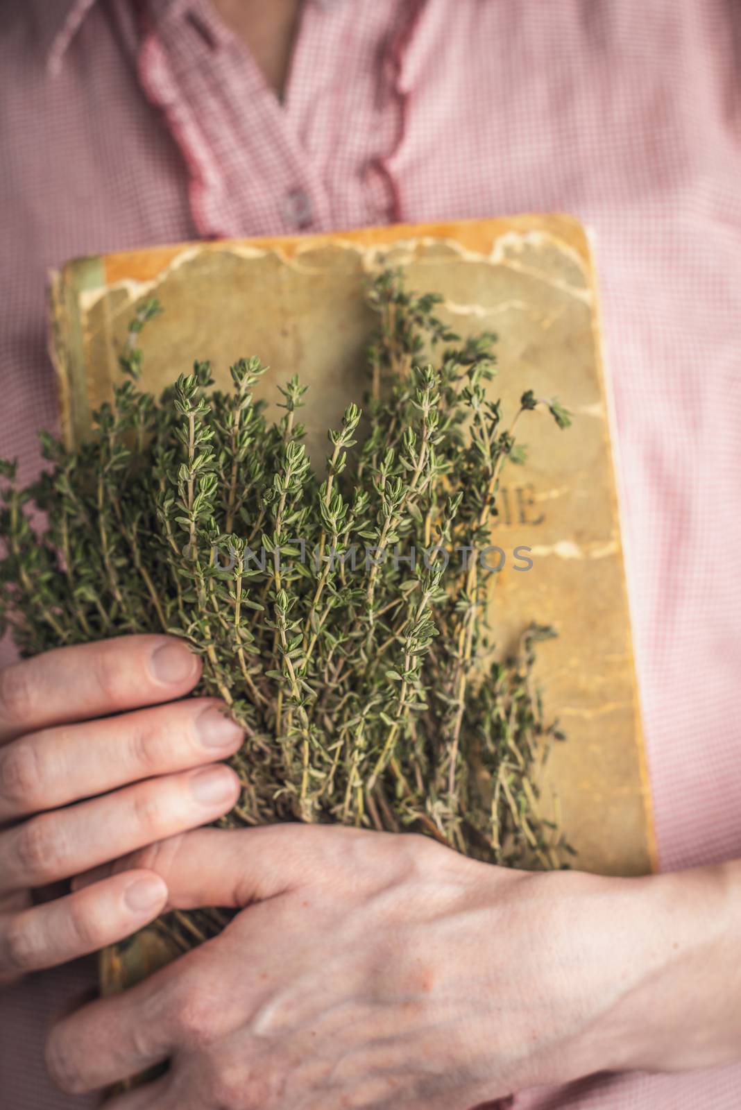 Woman holding old recipe book and herbs