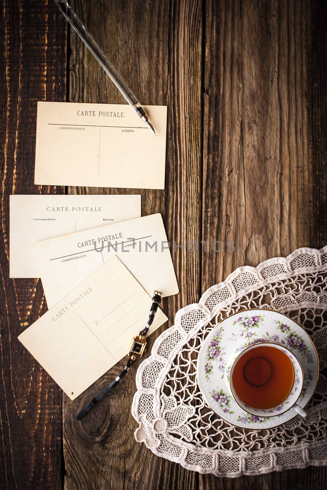 Postcards with cup of tea on the wooden table vertical