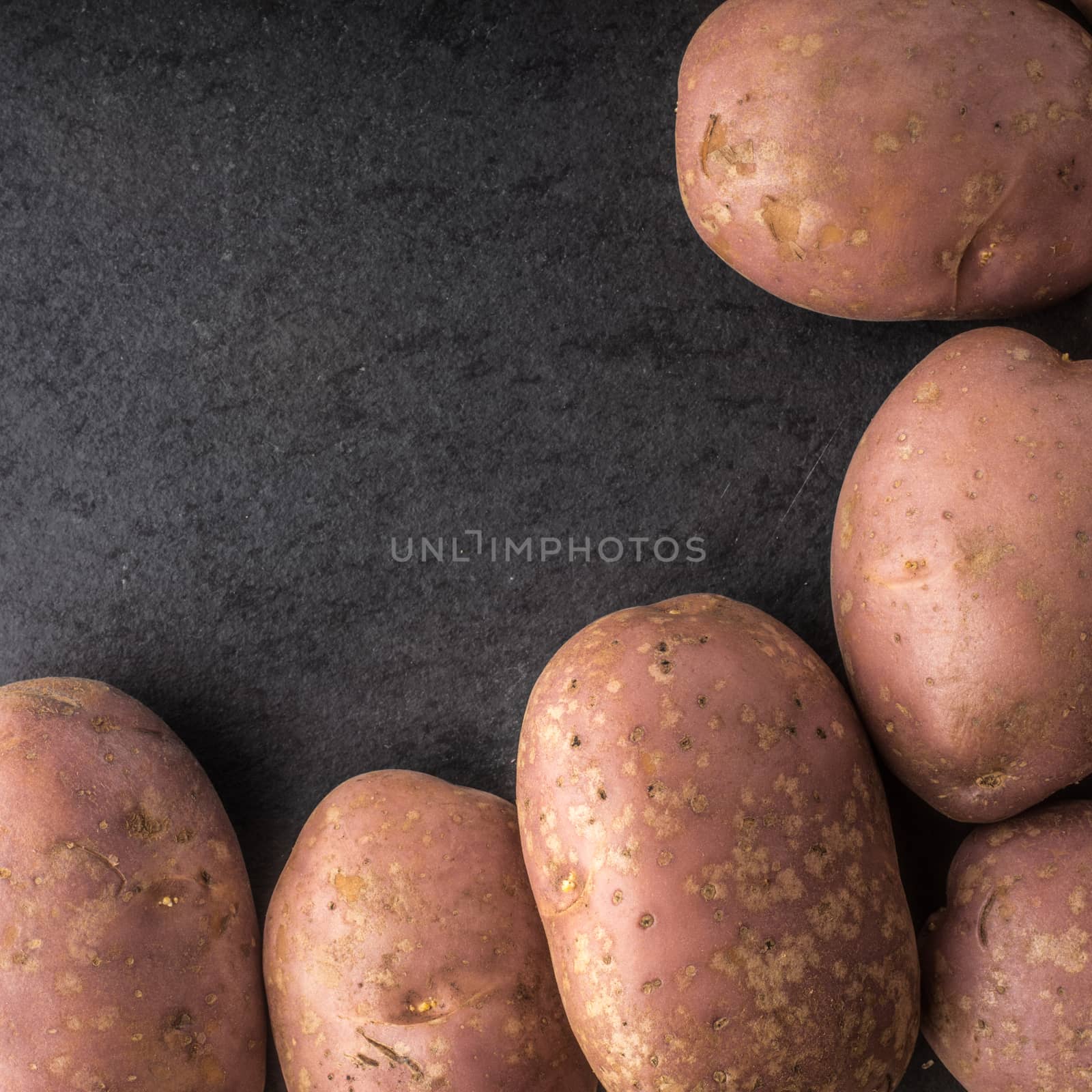 Raw potatoes at the  right of the black stone table square