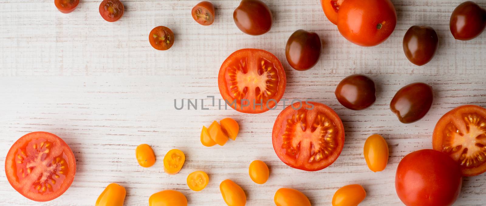 Tomatoes mix on the white table wide screen by Deniskarpenkov
