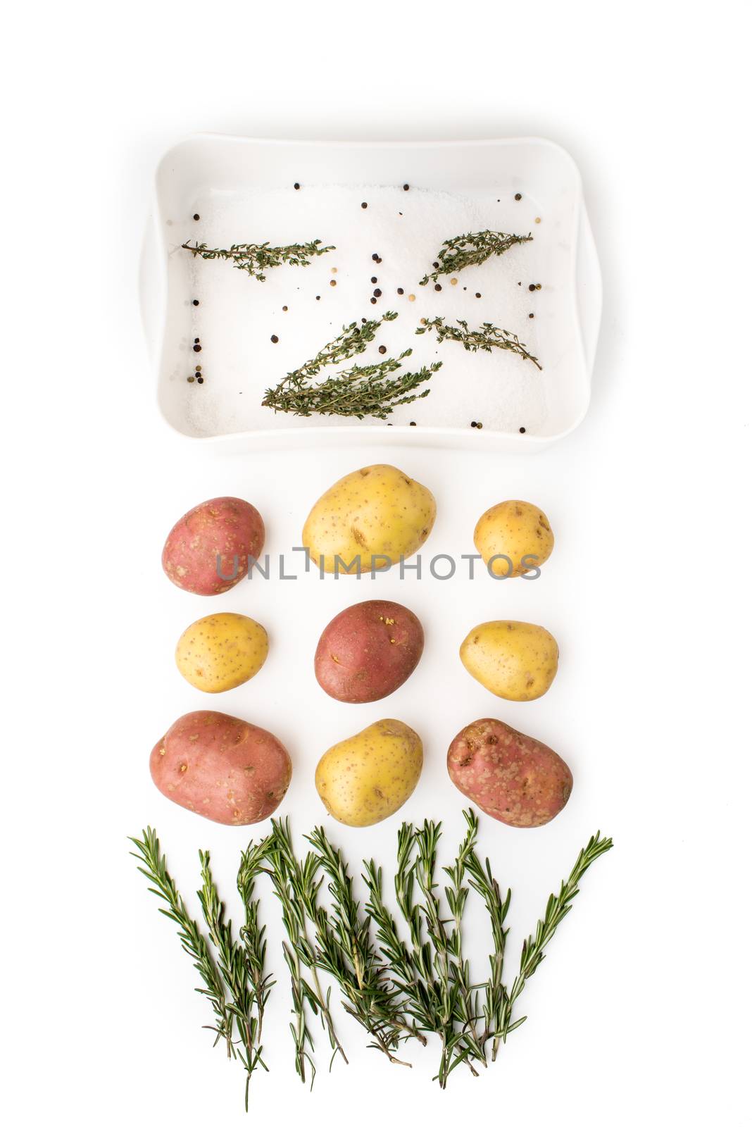 Raw potatoes with spices and herbs on the white background by Deniskarpenkov