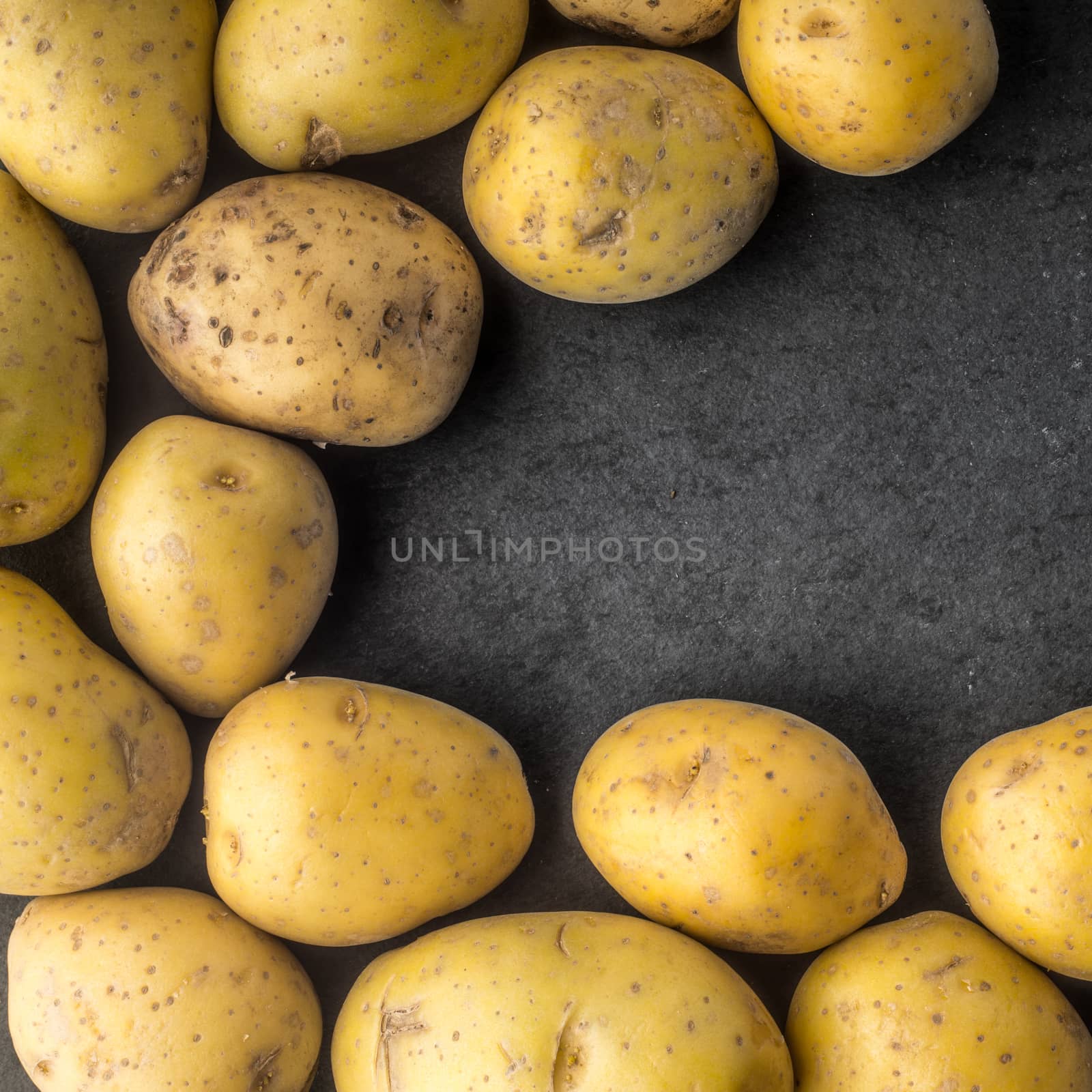 Potatoes on the dark stone table square by Deniskarpenkov