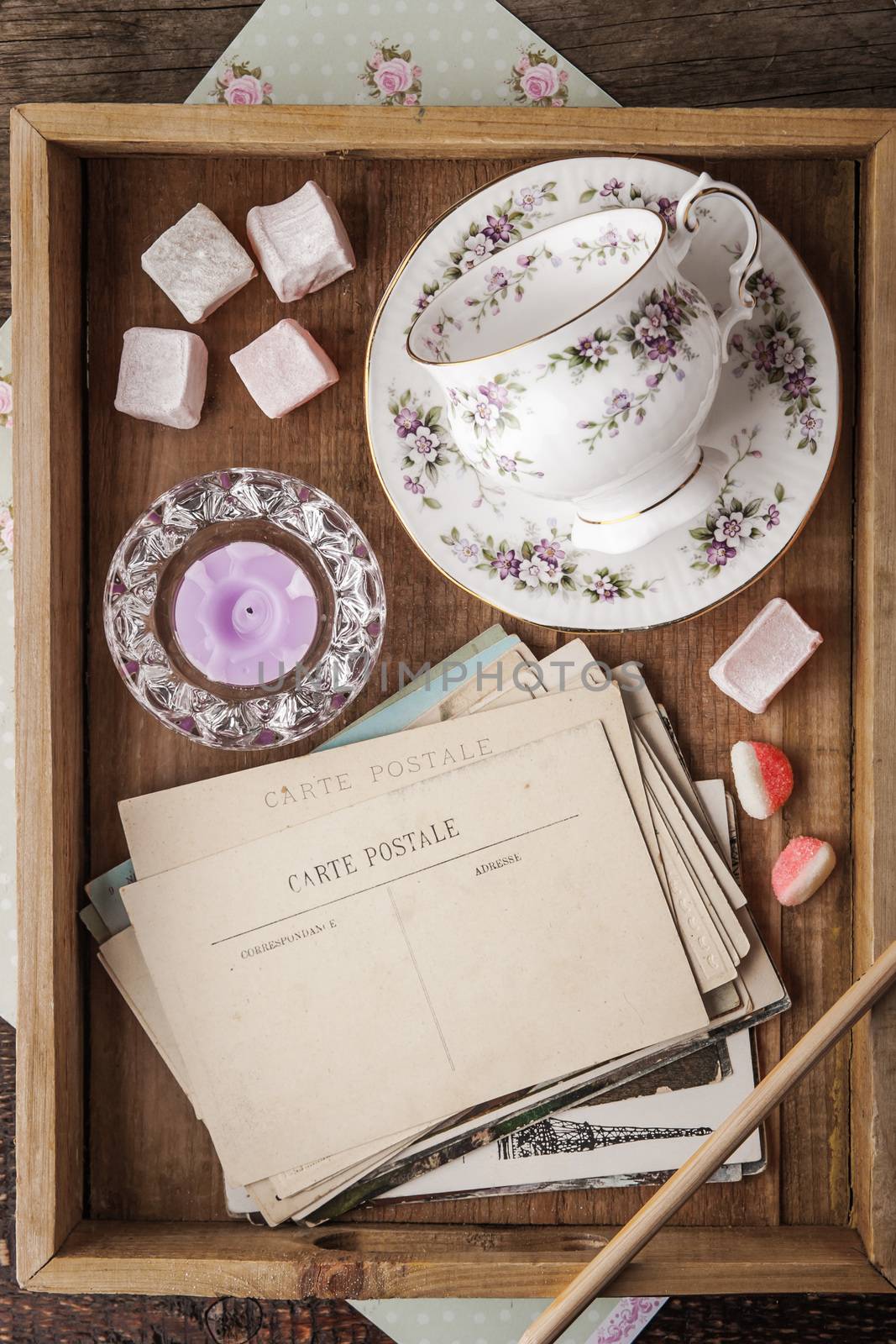Tea things with sweets and postcards on the wooden tray