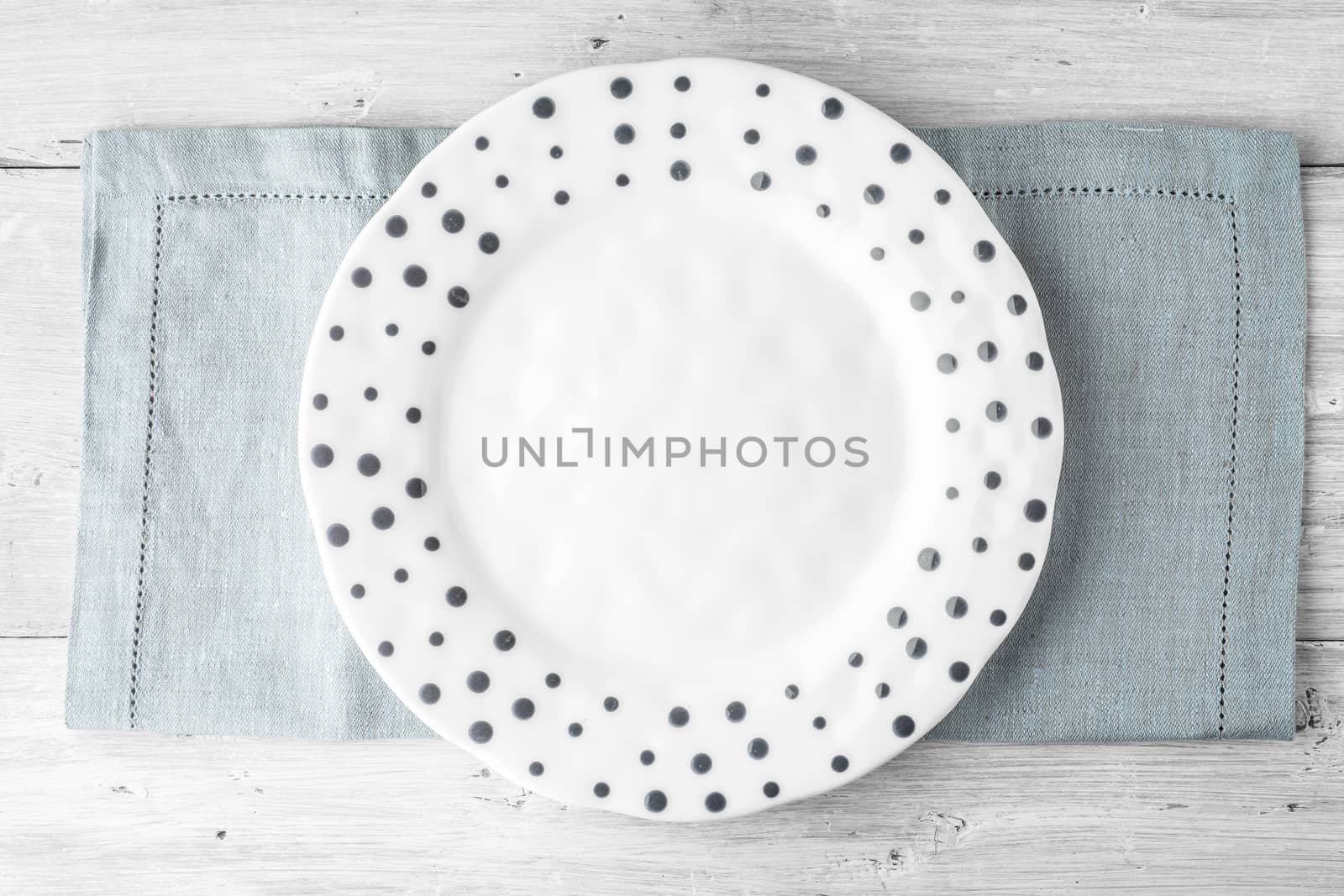 White plate with blue dot on the white wooden table