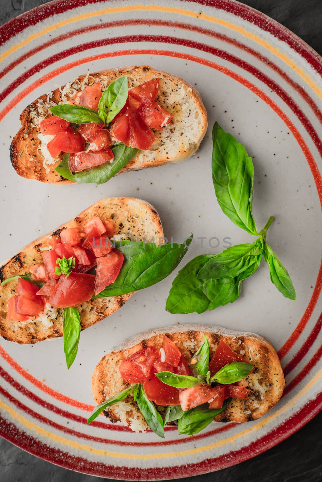 Bruschetta with tomatoes and basil on the colorful ceramic plate