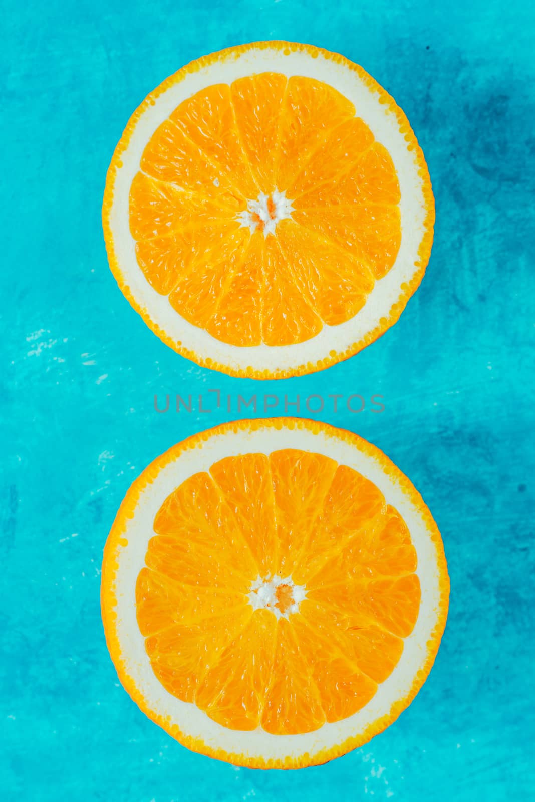 Halves of orange on the cyan background top view by Deniskarpenkov