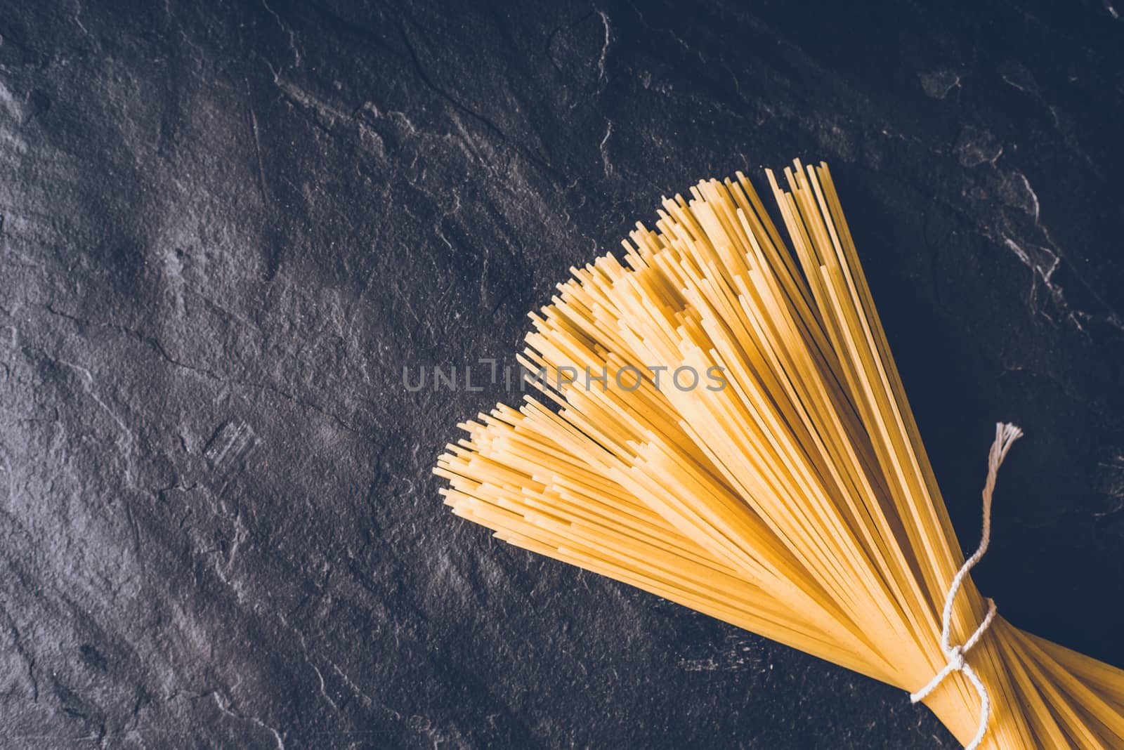 Raw spaghetti on the black stone background top view