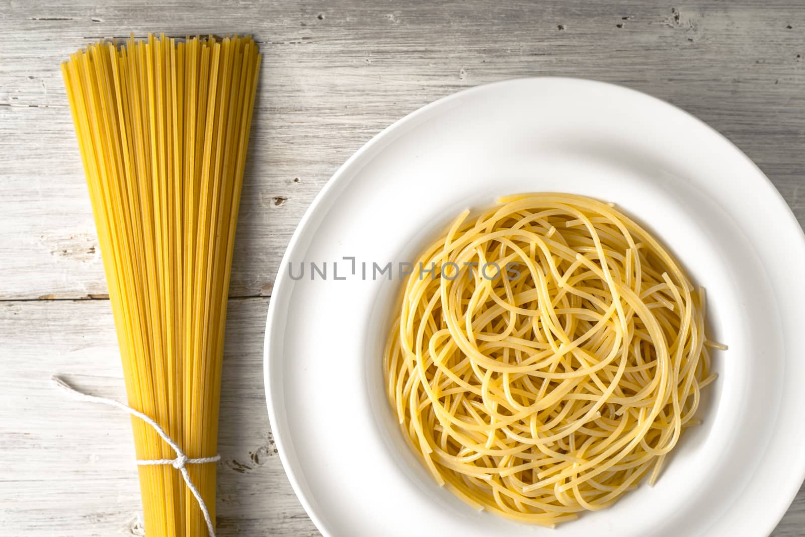 Raw and cooked spaghetti on the white wooden table horizontal