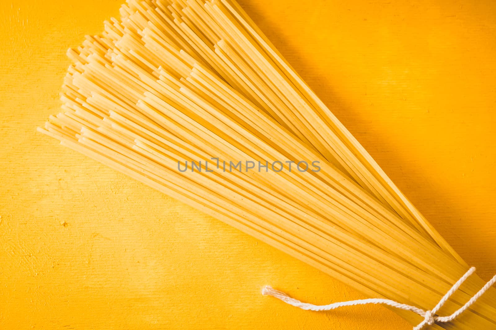 Raw spaghetti on the yellow background top view