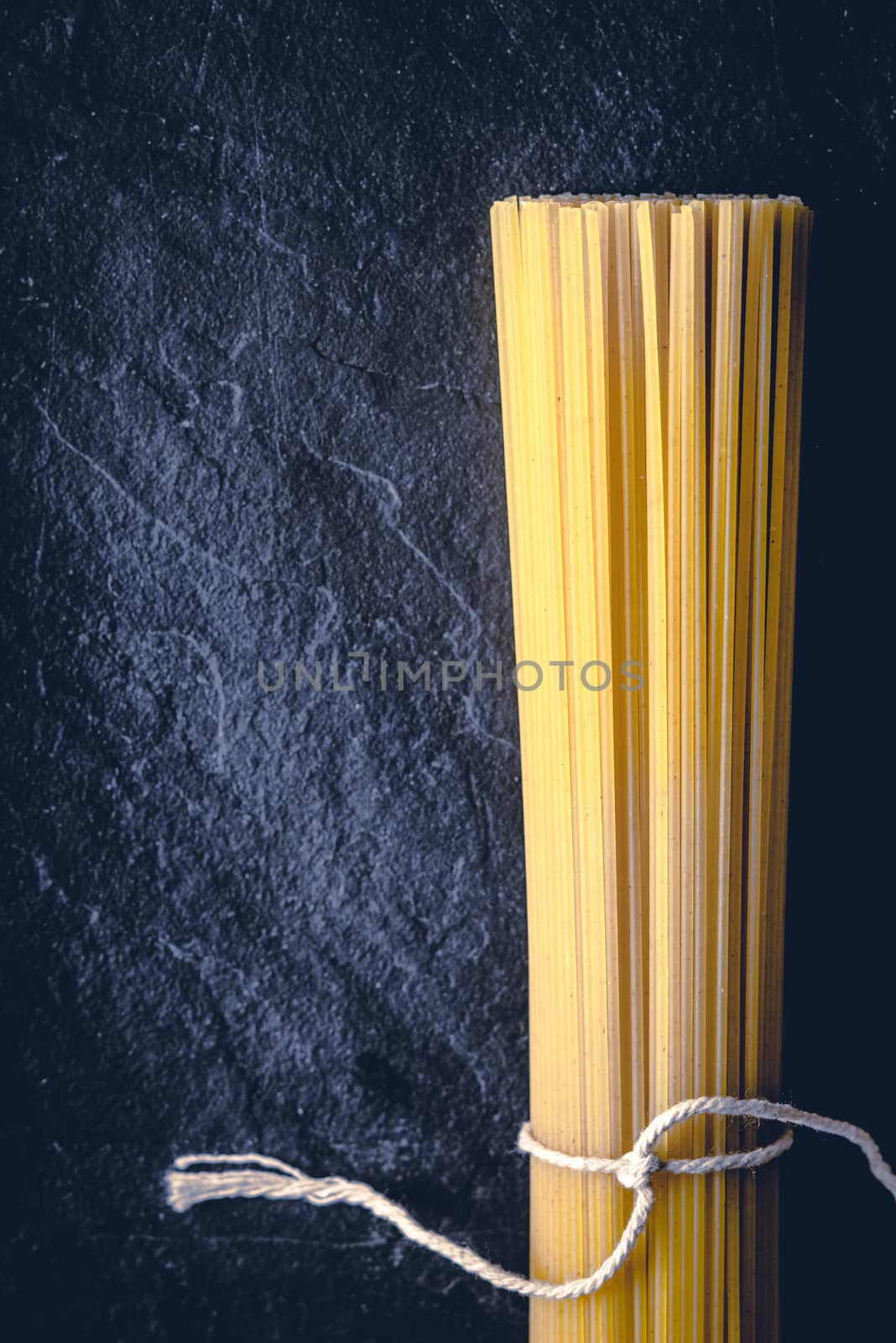 Raw spaghetti on the black stone background  vertical