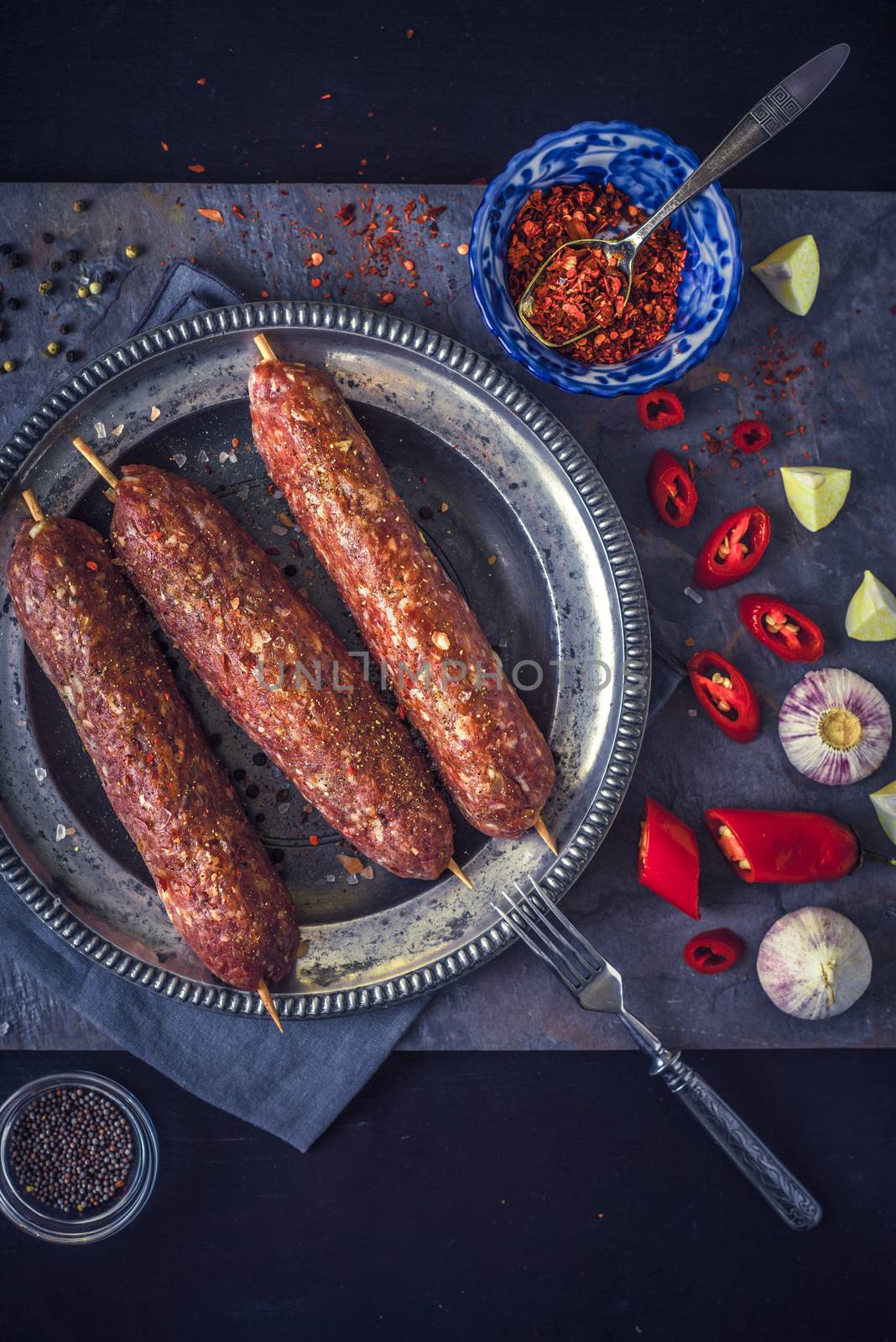 Raw kebabs with seasoning on the stone table vertical by Deniskarpenkov