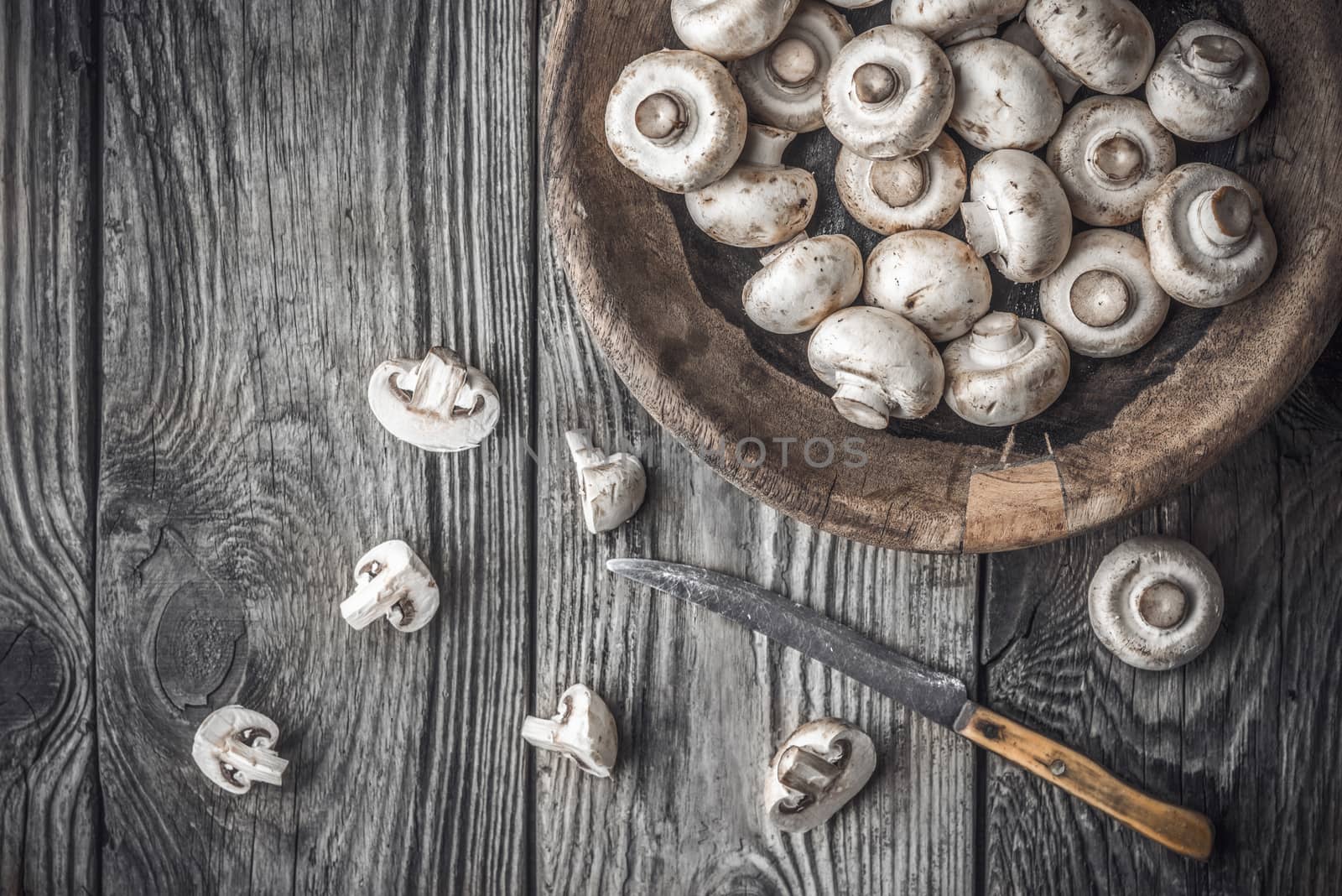 Champignon on the wooden bowl on the old table horizontal