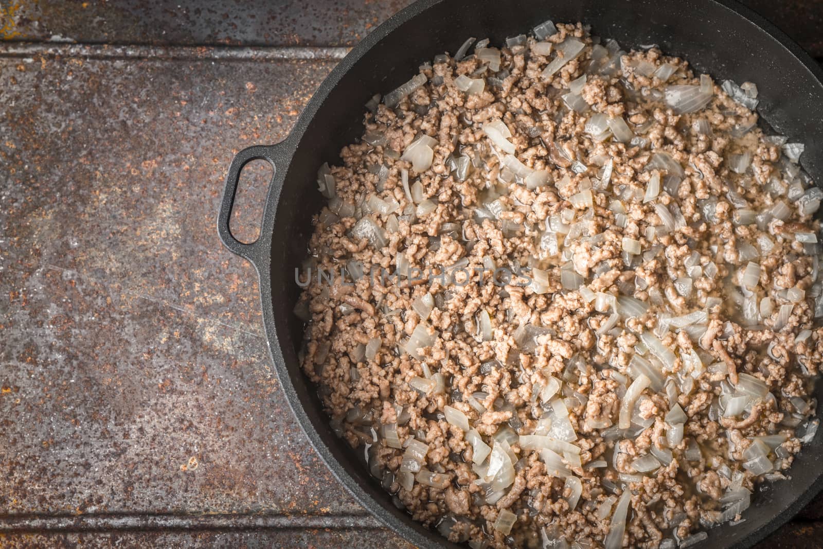 Fried minced meat with onion on the pan on the metal background top view