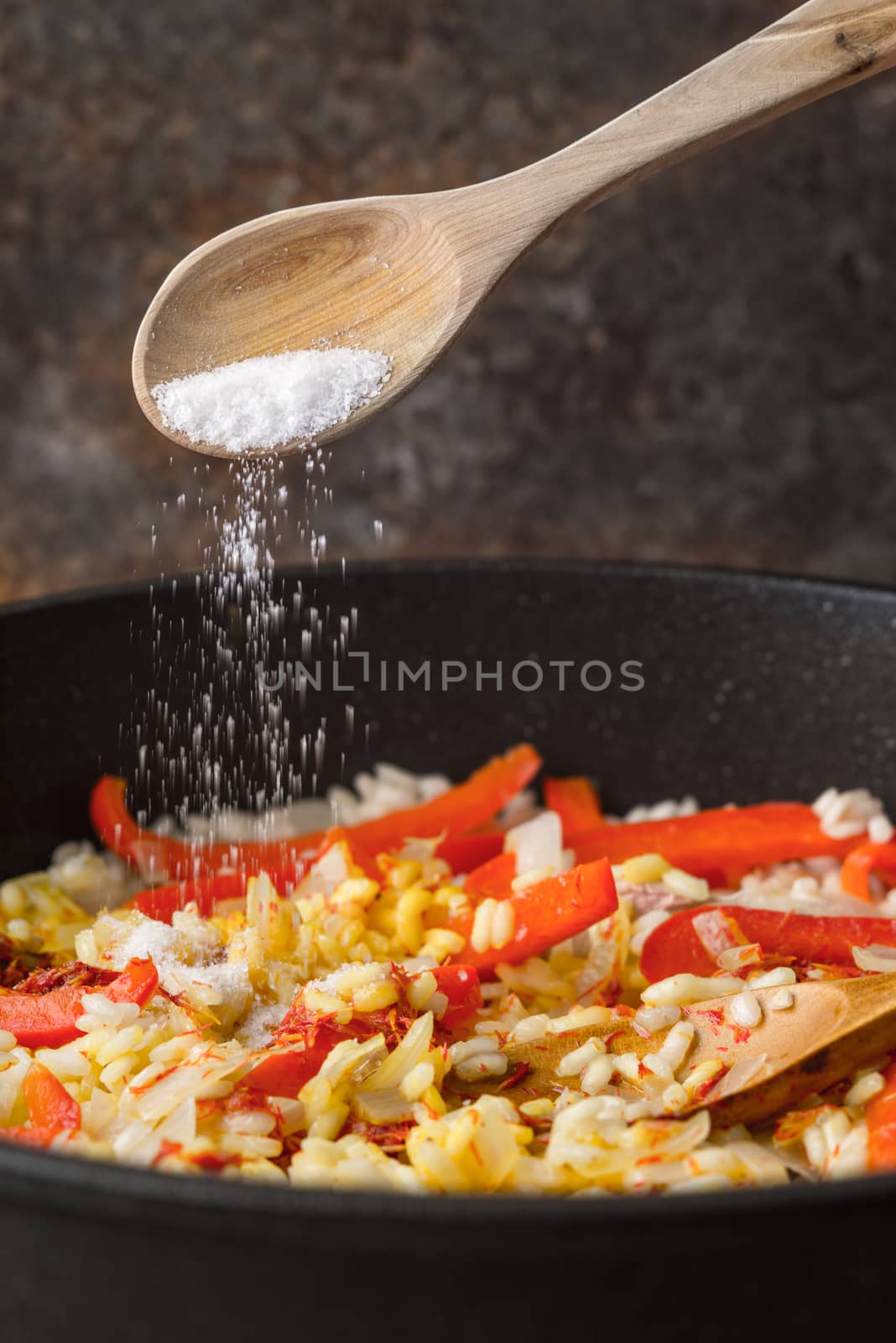 Adding salt in the pan with rice and bell pepper vertical by Deniskarpenkov