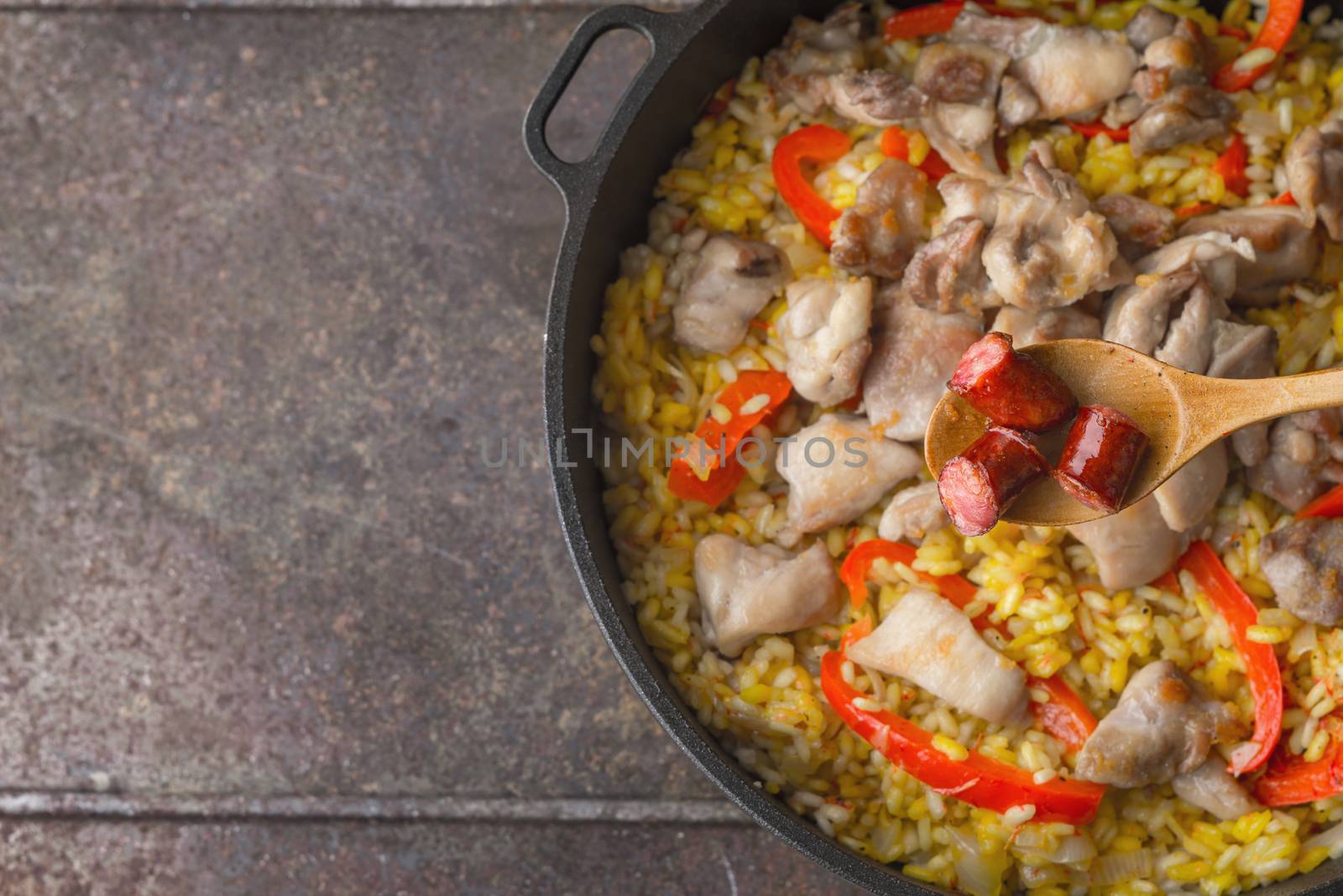Spoon with smoked  sausages on the pan with cooking paella by Deniskarpenkov