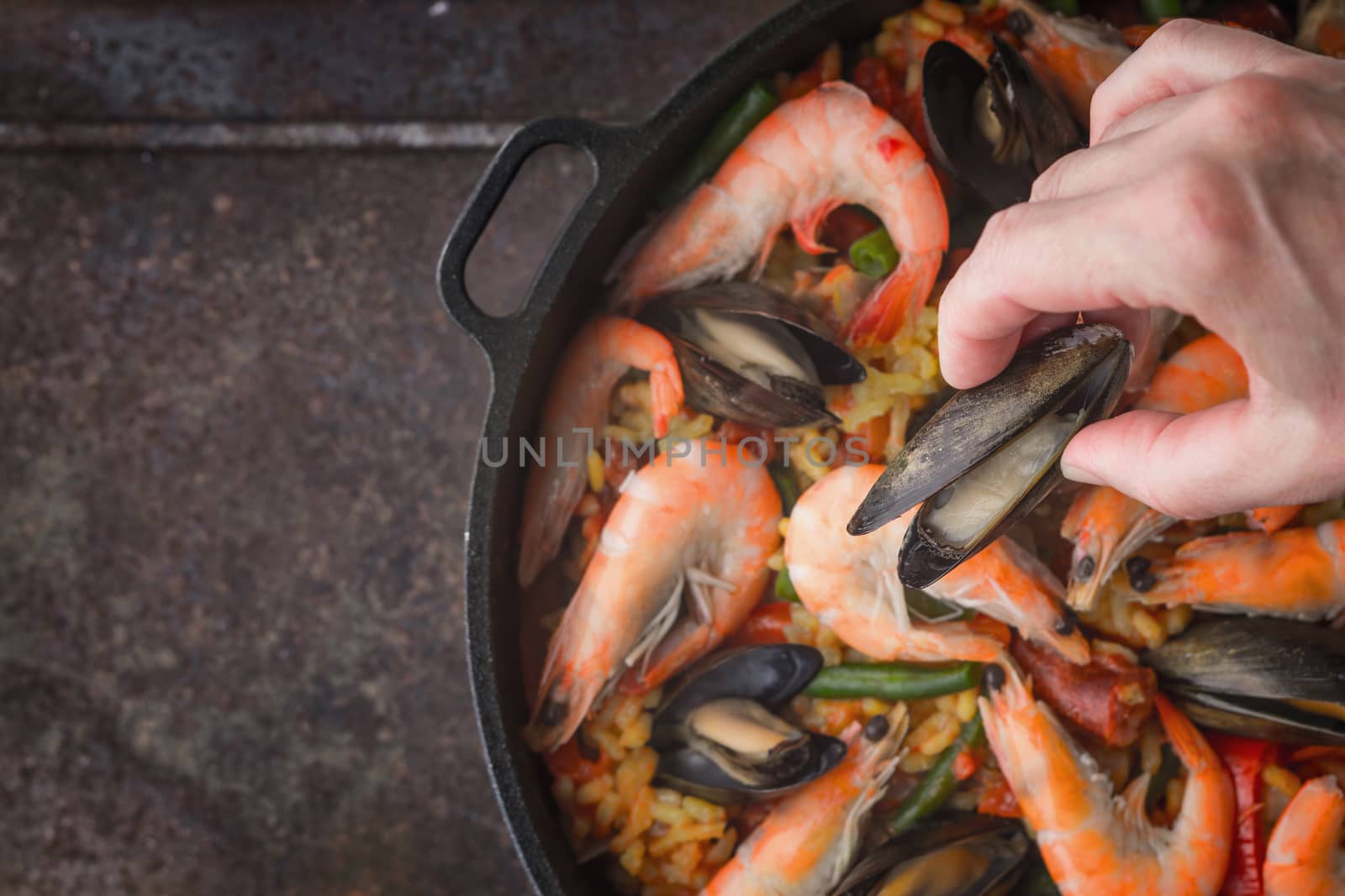 Adding mussels on the pan with cooking paella top view by Deniskarpenkov
