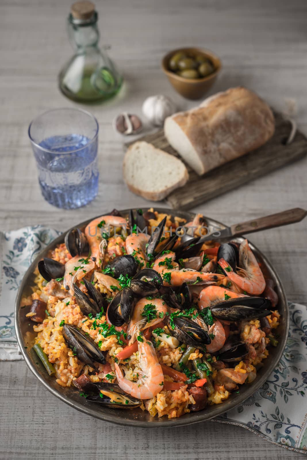 Paella in the metal plate on the wooden table by Deniskarpenkov