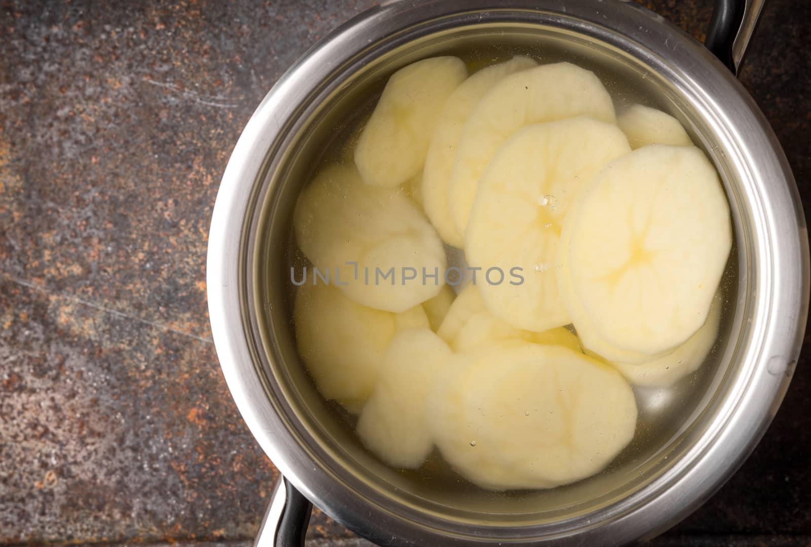 Sliced potatoes in the metal pot with water by Deniskarpenkov