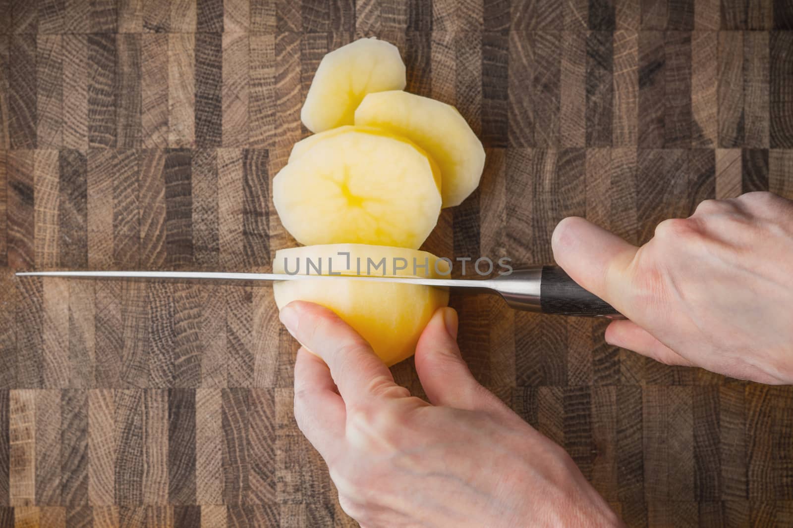 Cutting potatoes on the wooden board horizontal by Deniskarpenkov