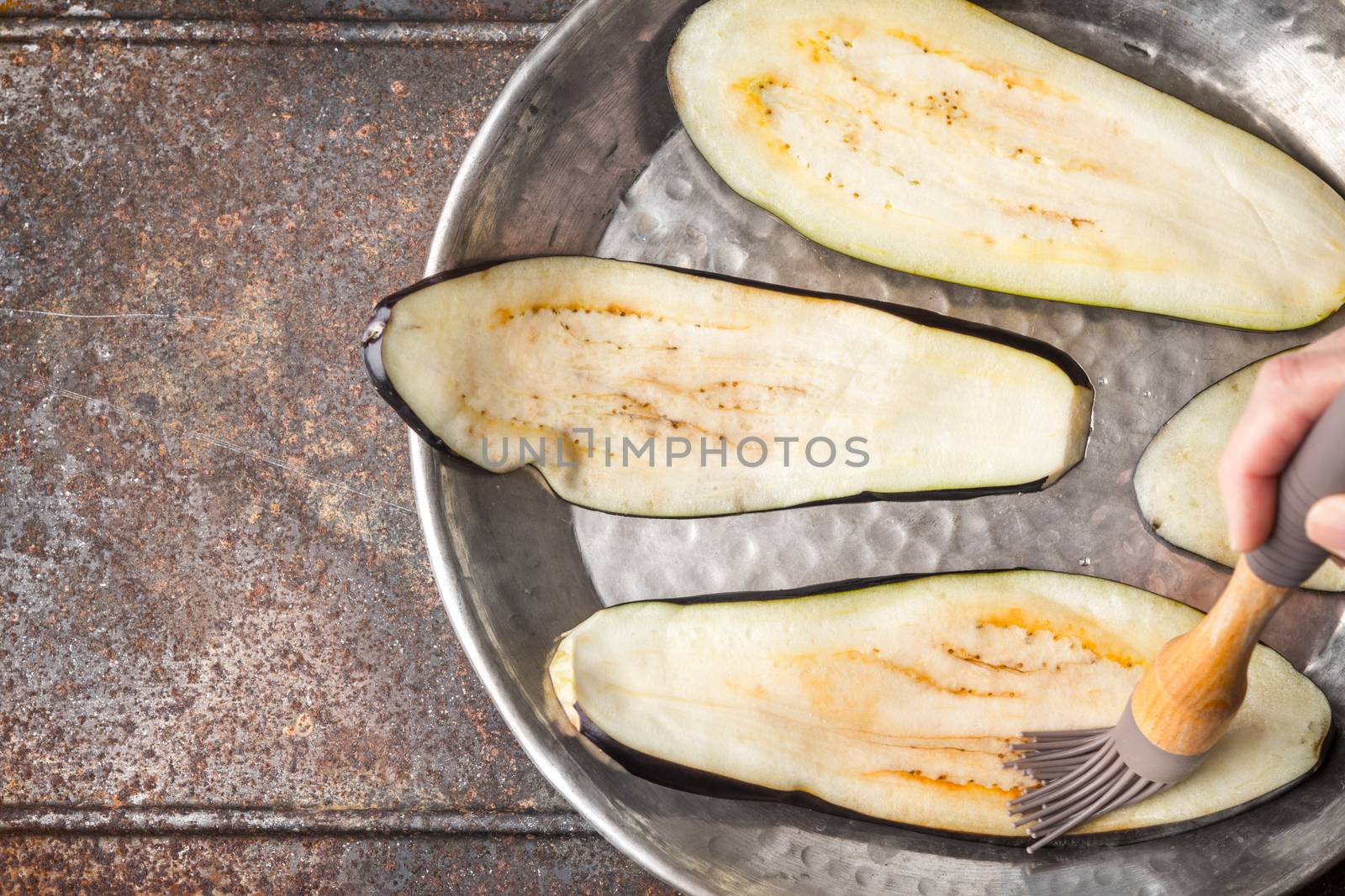 Brush the eggplant slices with olive oil top view by Deniskarpenkov