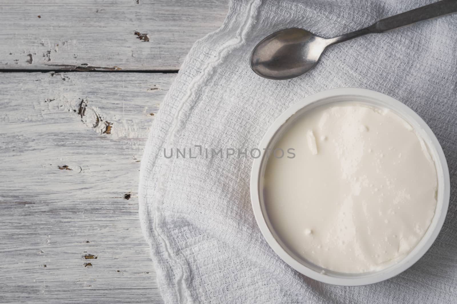 Ricotta with spoon and napkin on the white wooden table horizontal by Deniskarpenkov