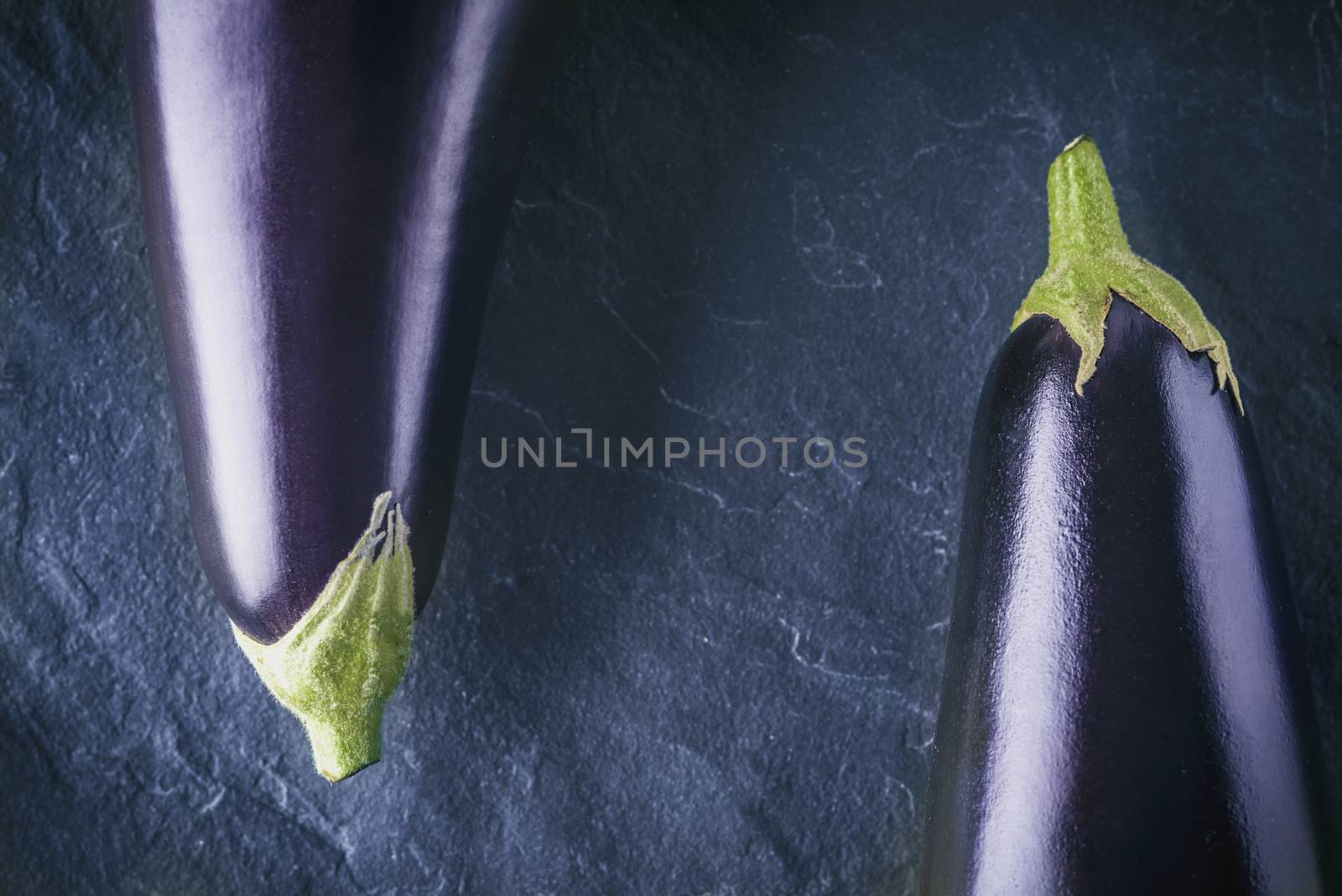 Eggplants on the dark stone background top view by Deniskarpenkov