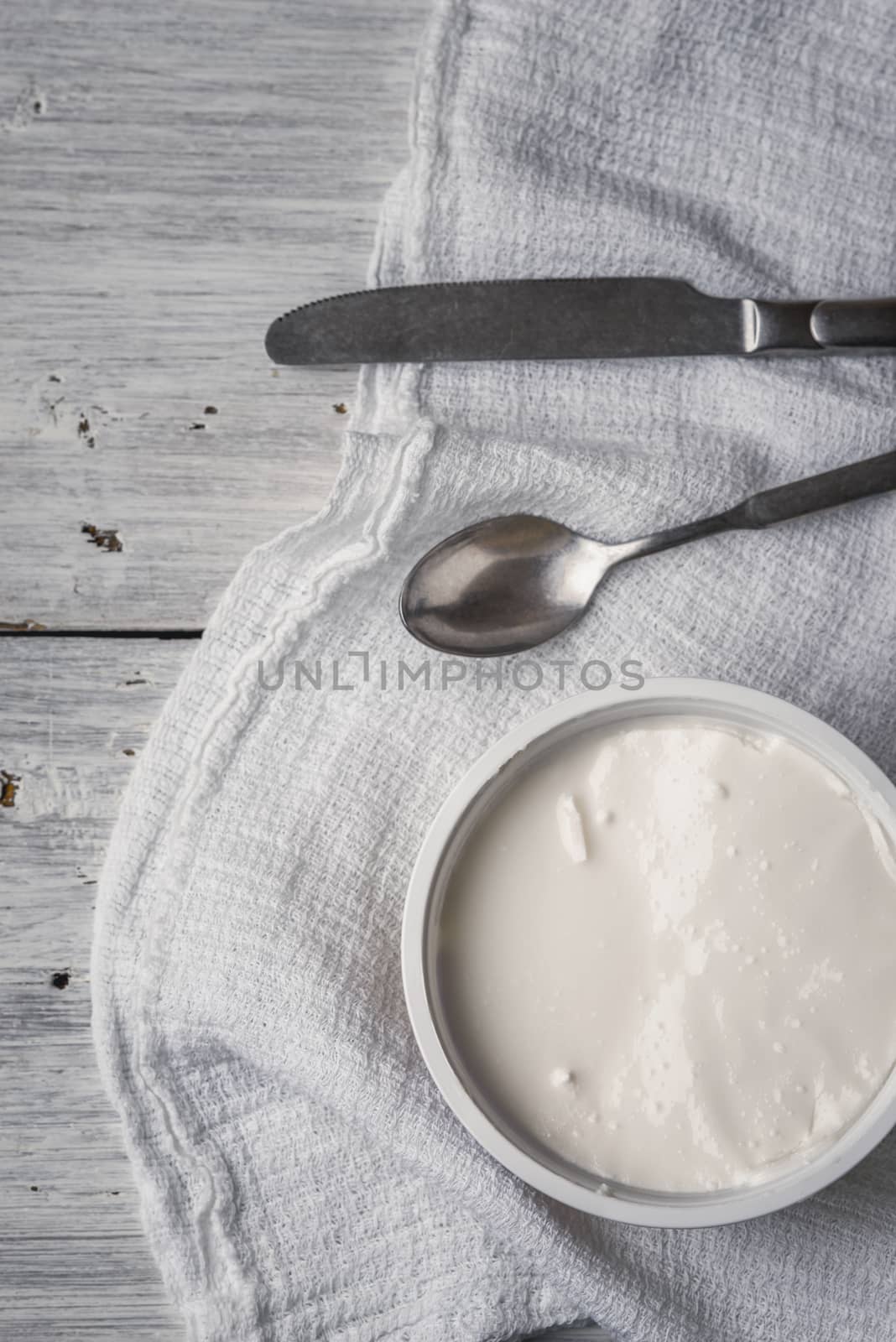 Ricotta with cutlery and napkin on the white wooden table vertical