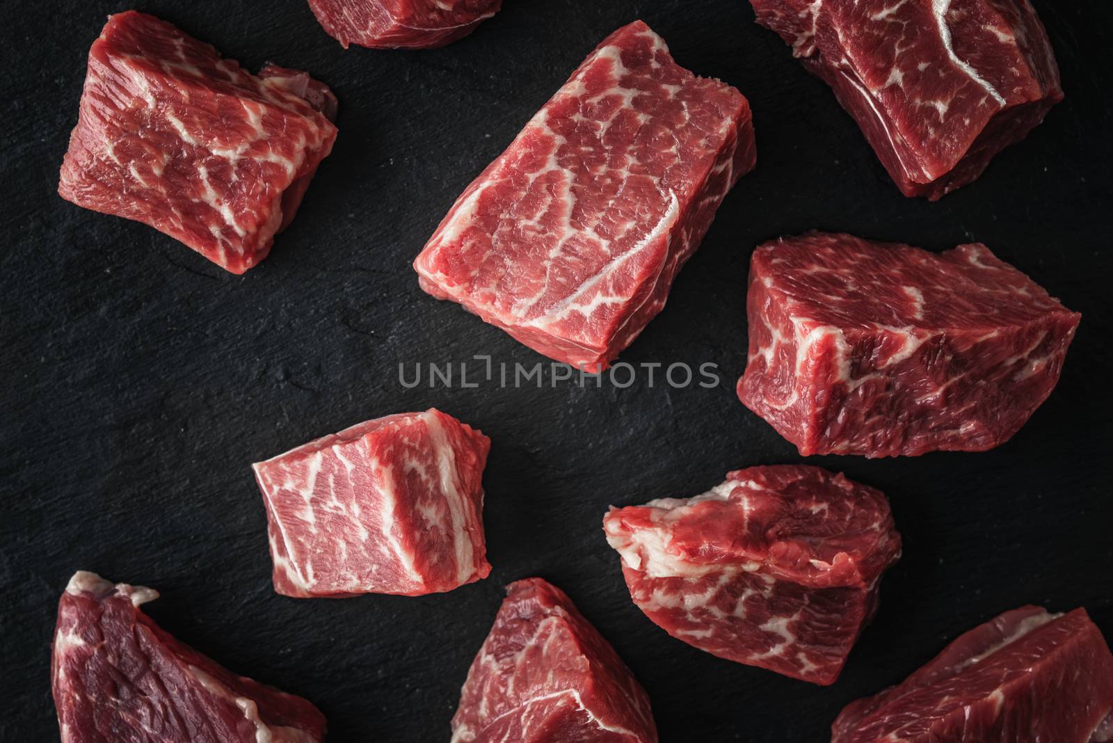 Raw angus beef slices on the black stone  table top view by Deniskarpenkov