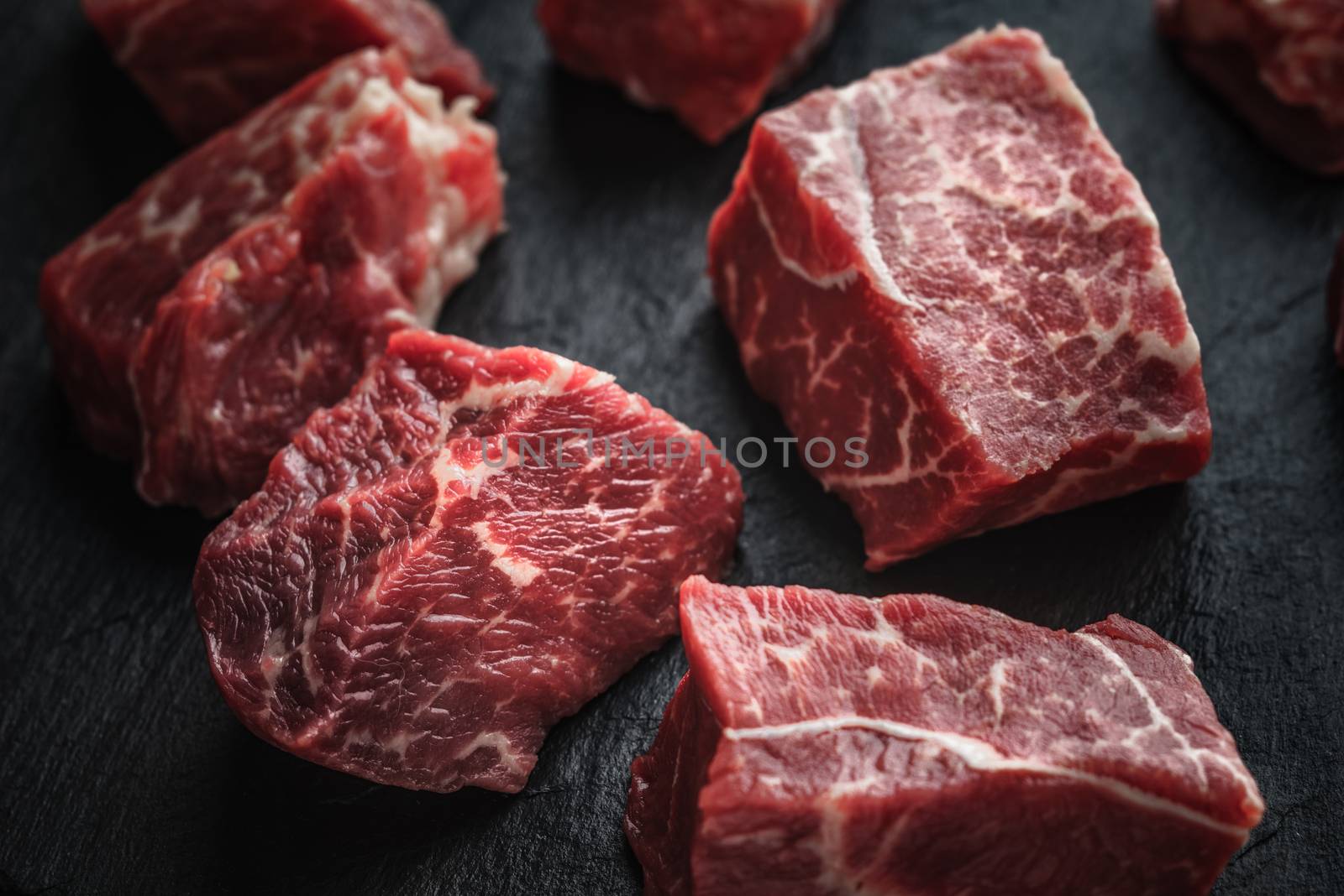 Raw angus beef slices on the black stone  table horizontal by Deniskarpenkov
