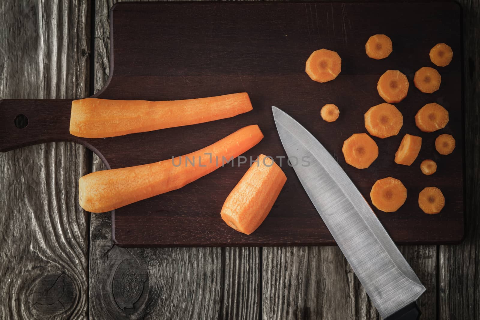Cutting carrots on the wooden board top view