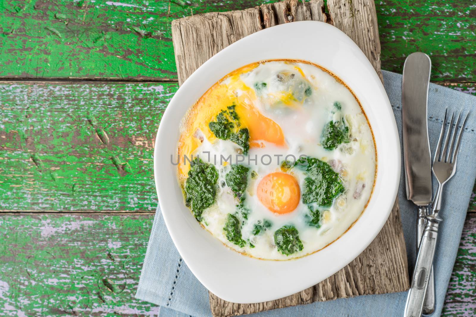 Florentine eggs with pureed spinach on the wooden table top view by Deniskarpenkov