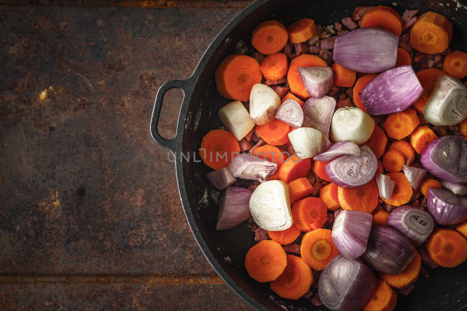 Shallot and carrots in the pan on the metal background