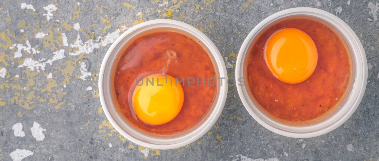 Raw eggs with tomatoes in the ramekins on the stone table wide screen