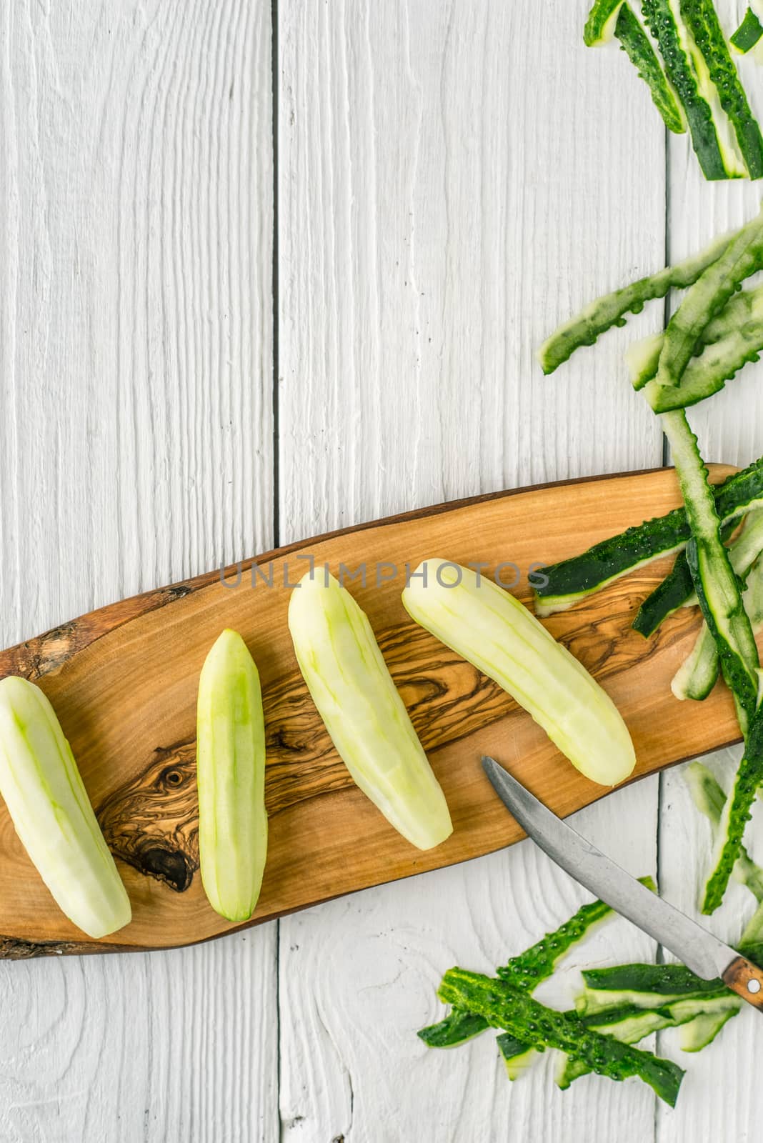 Peeled cucumbers on the wooden board  on the white table vertical