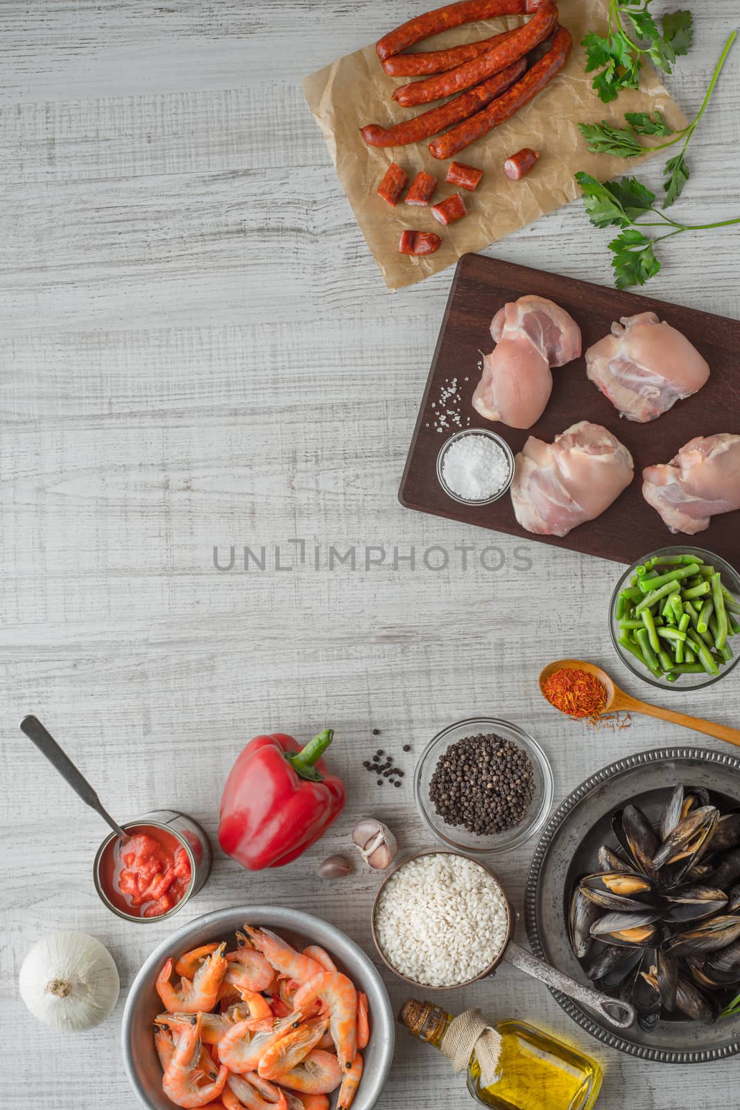 Ingredients for paella on the white  wooden table vertical by Deniskarpenkov