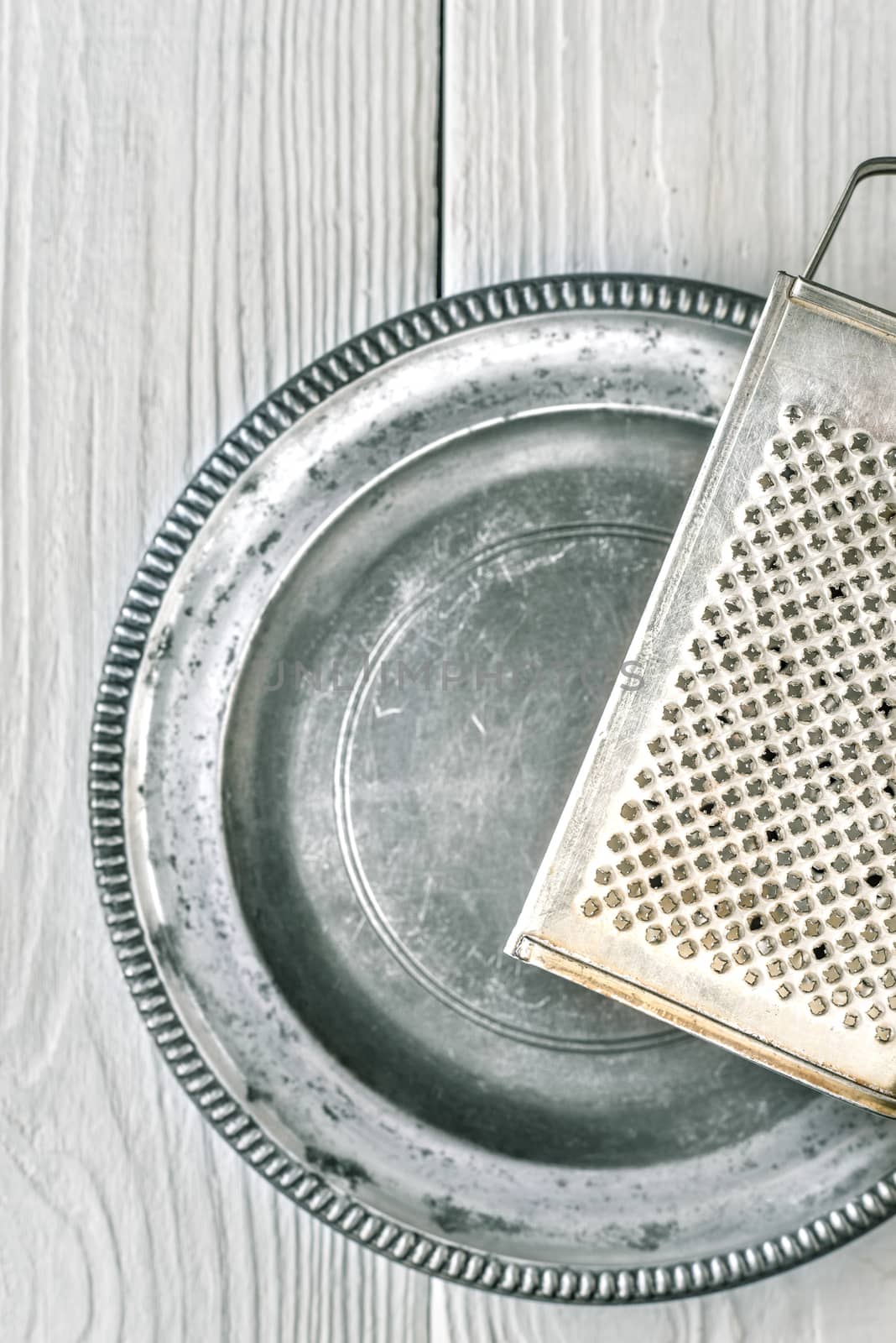 Metal plate with grater on the white wooden table