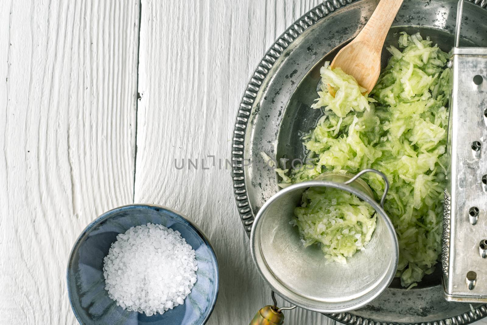 Grated cucumber with strainer and salt on the white table  top view