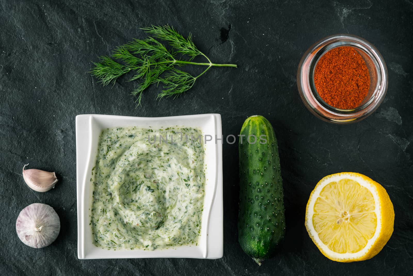 Tzatziki  on the stone table with cucumber , lemon and seasoning top view by Deniskarpenkov