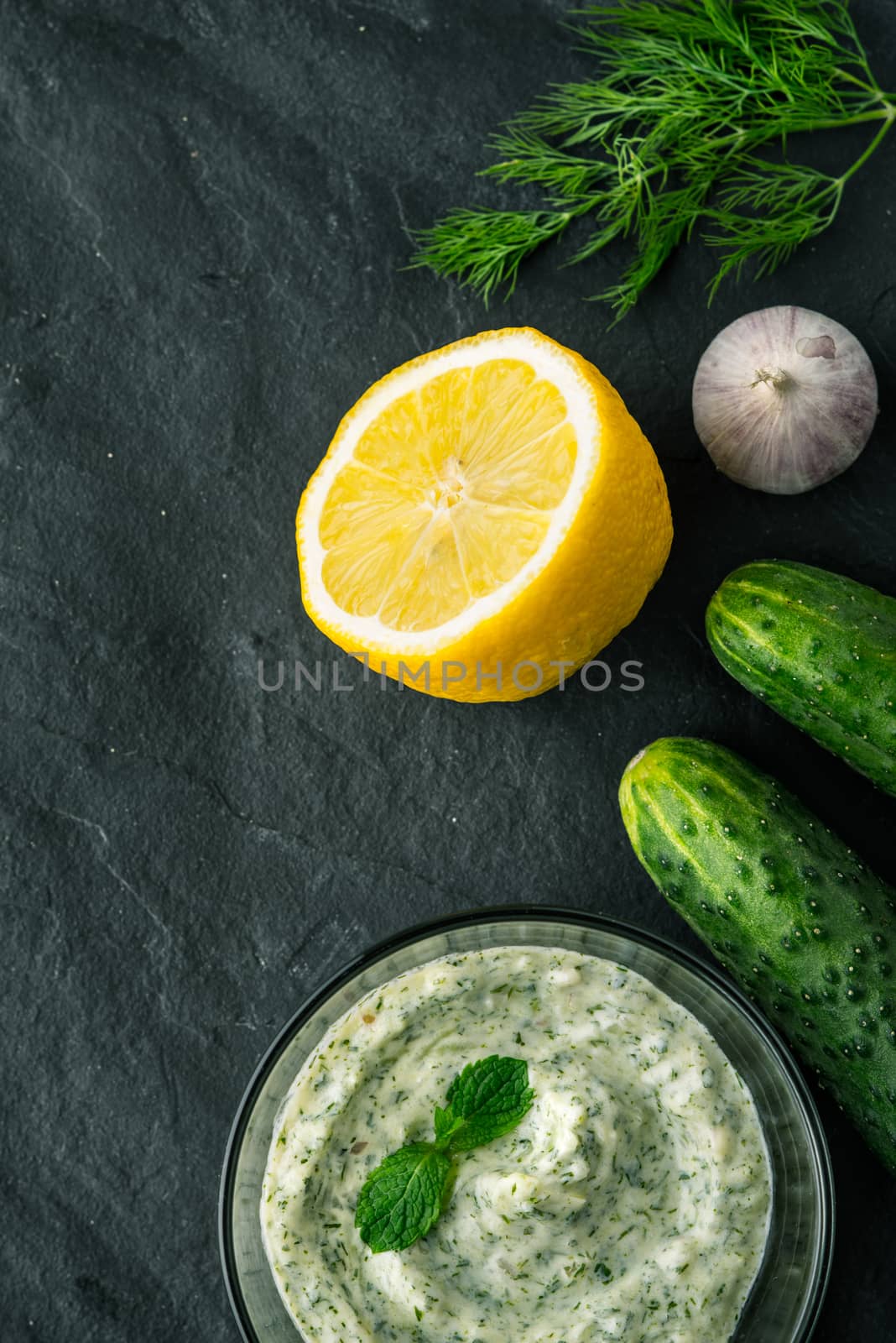 Tzatziki  on the dark stone table with ingredients vertical