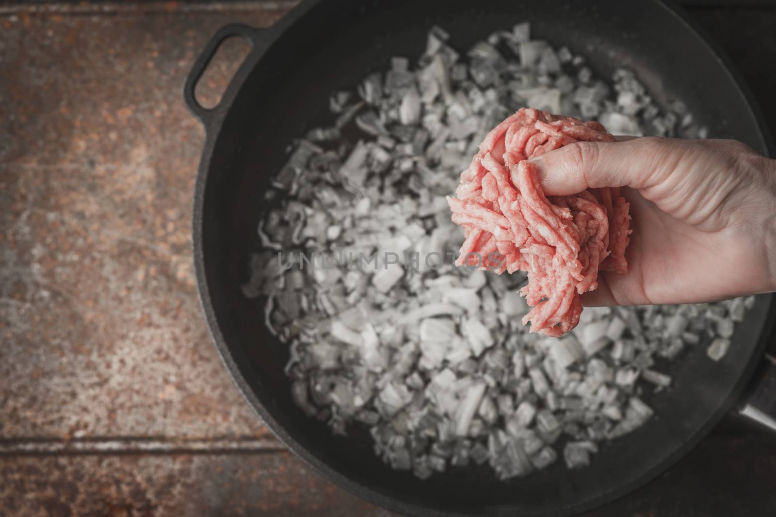 Raw minced meat in the hand with blurred pan top view by Deniskarpenkov