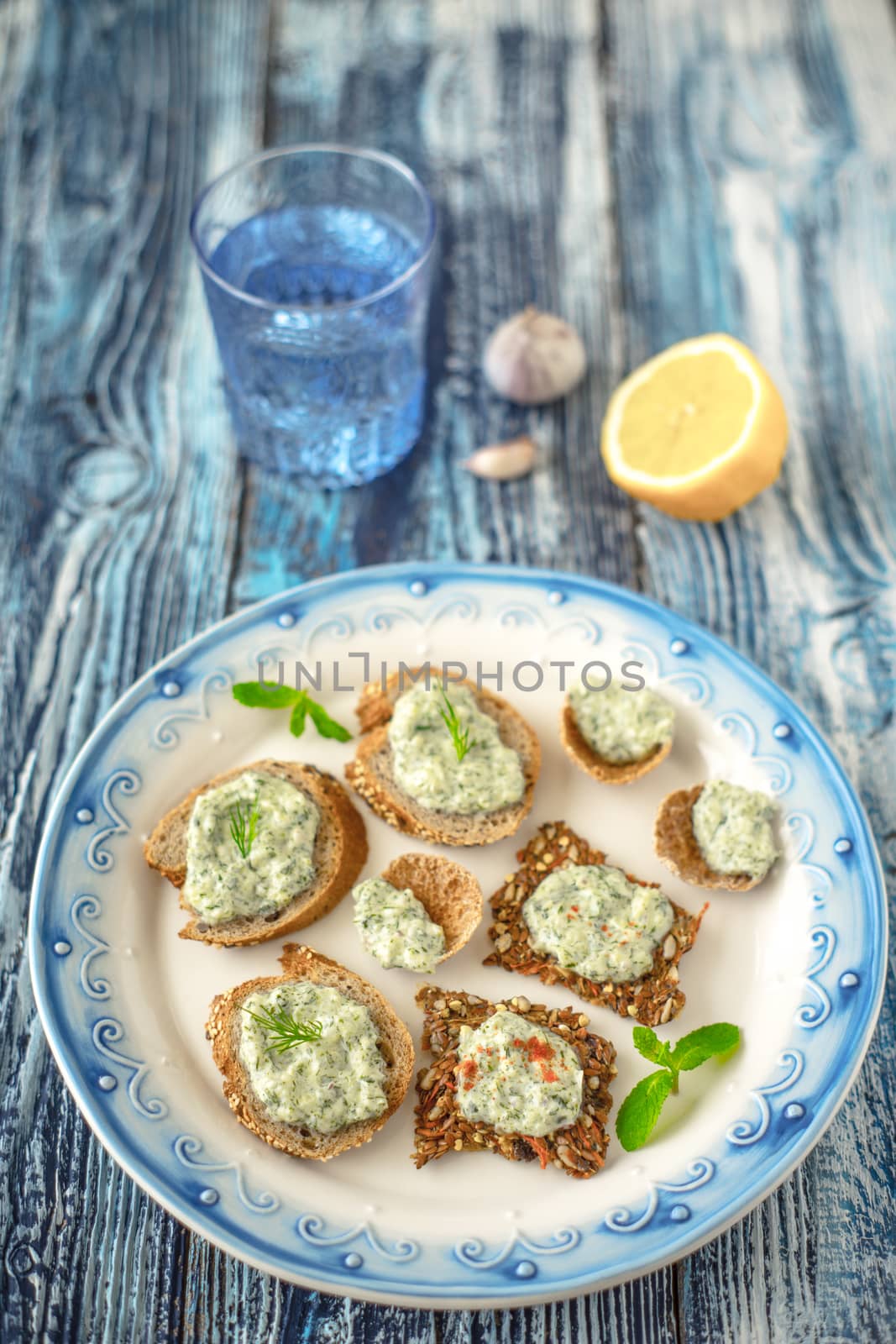 Plate with different bread with tzatziki on the blue table by Deniskarpenkov