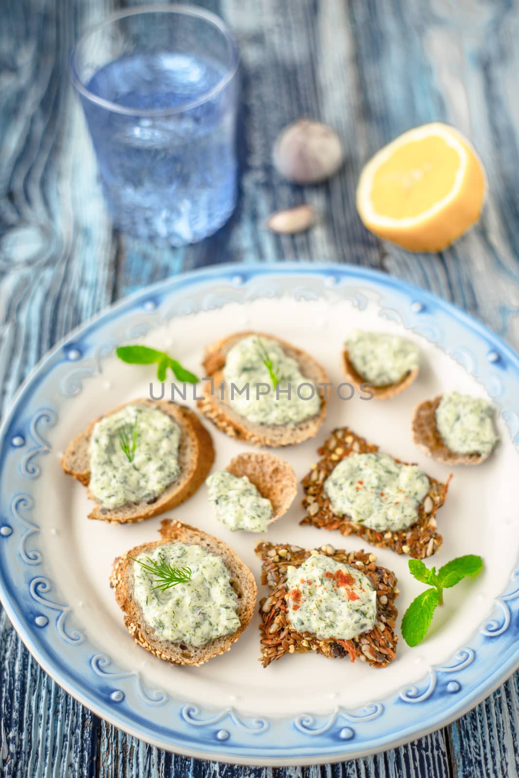 Plate with different bread with tzatziki on the blue table vertical by Deniskarpenkov