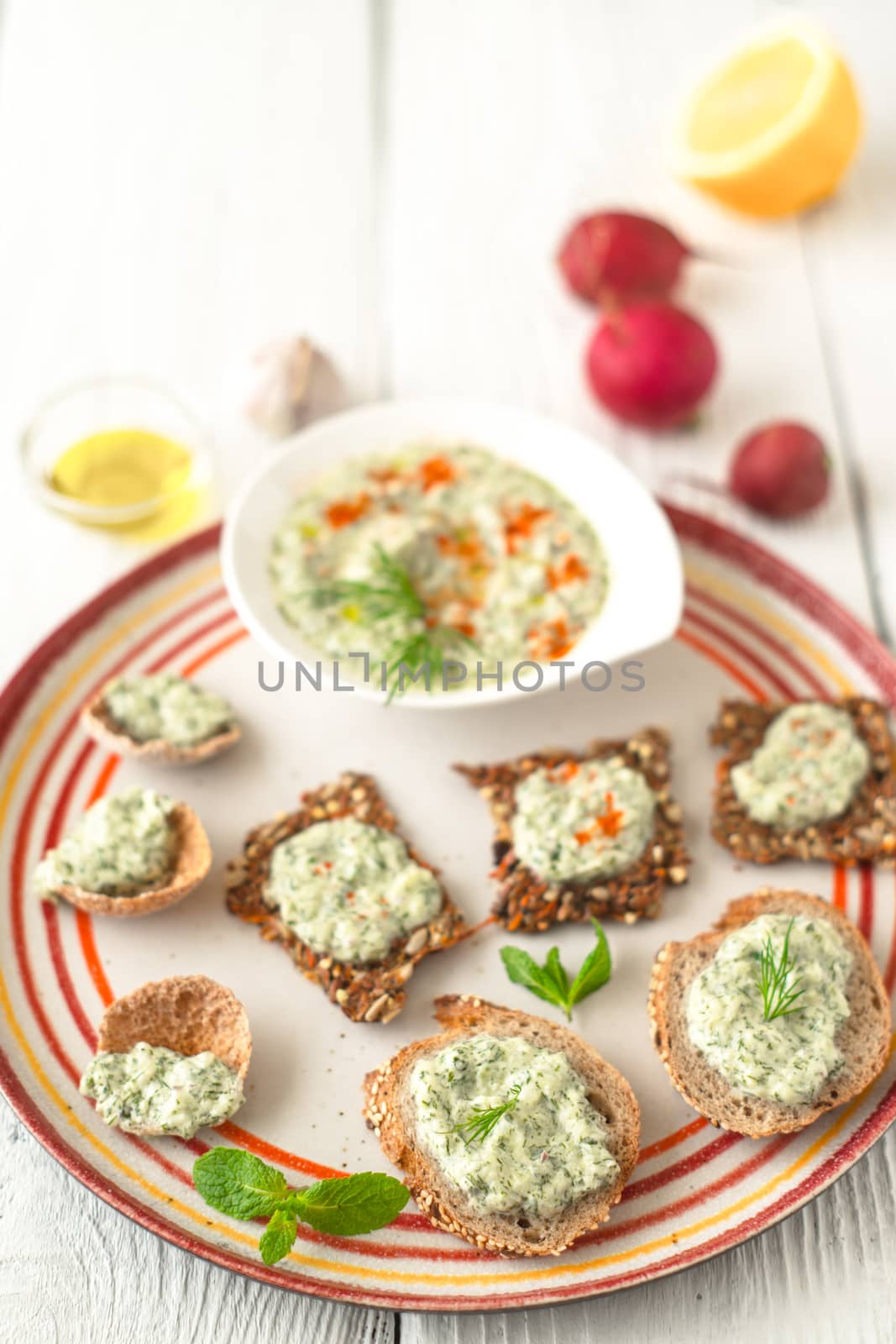 Colorful plate with different bread with tzatziki on the white table