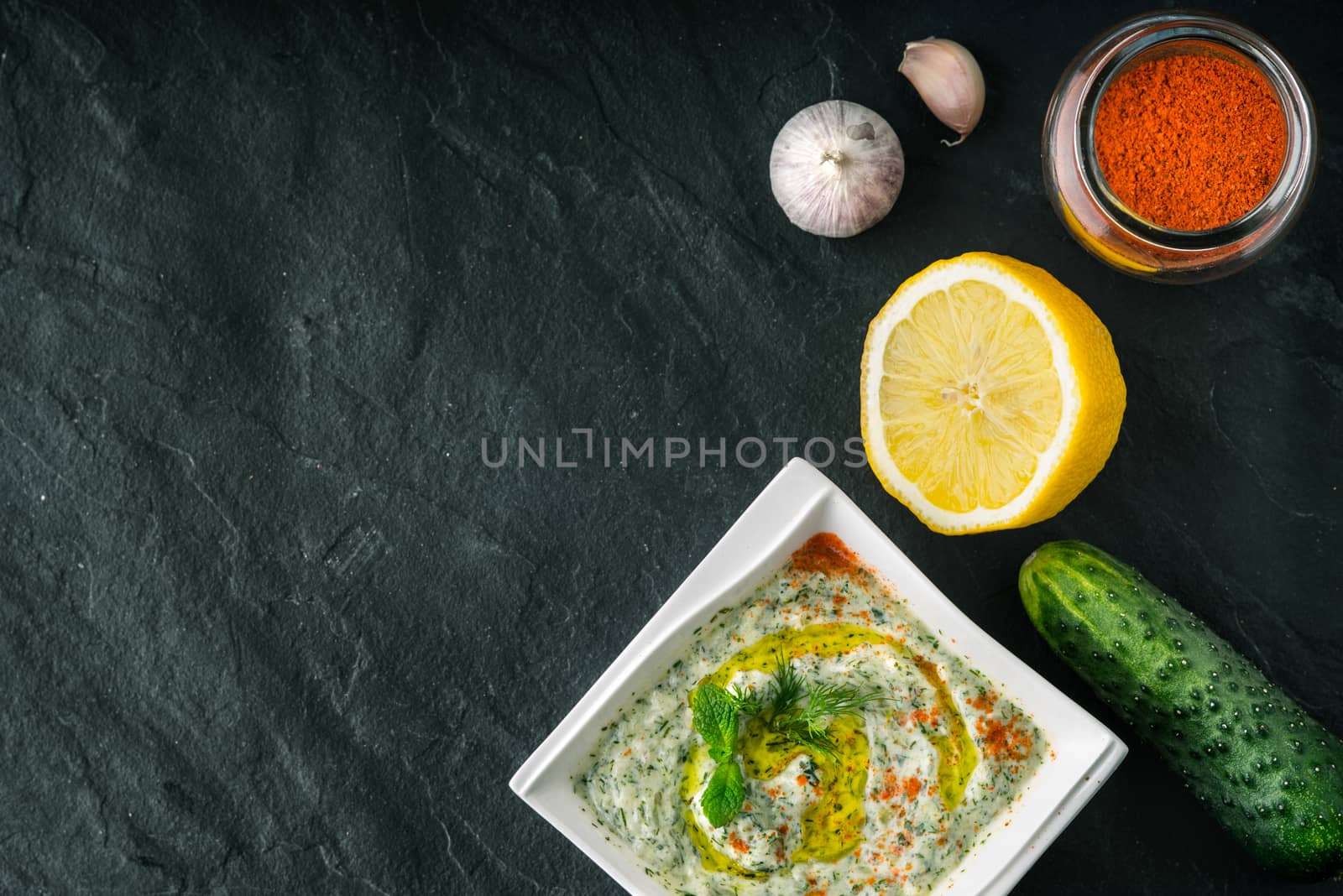 Tzatziki  on the  stone table with vegetables and seasoning top view